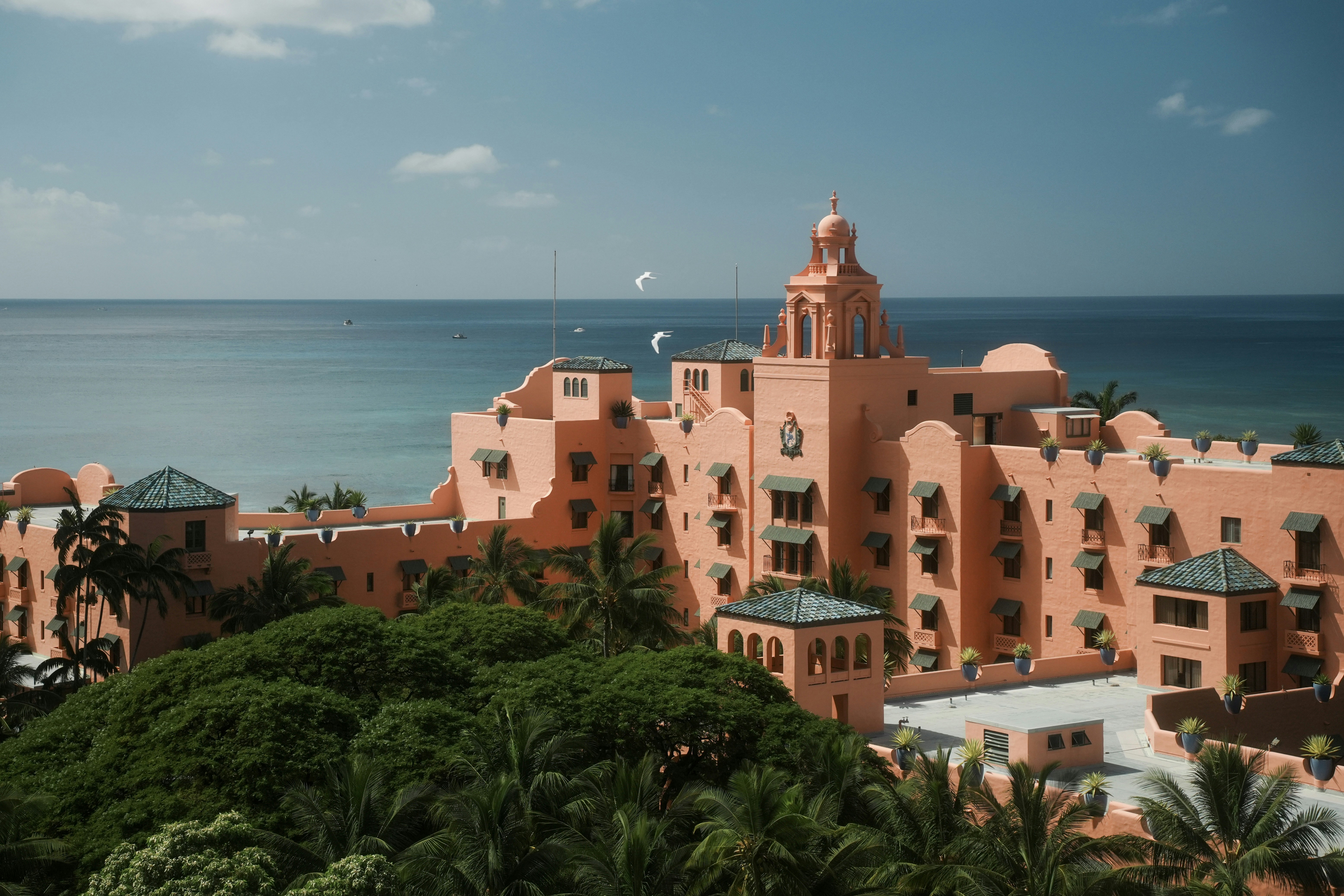 Pink historic hotel by the ocean with palm trees