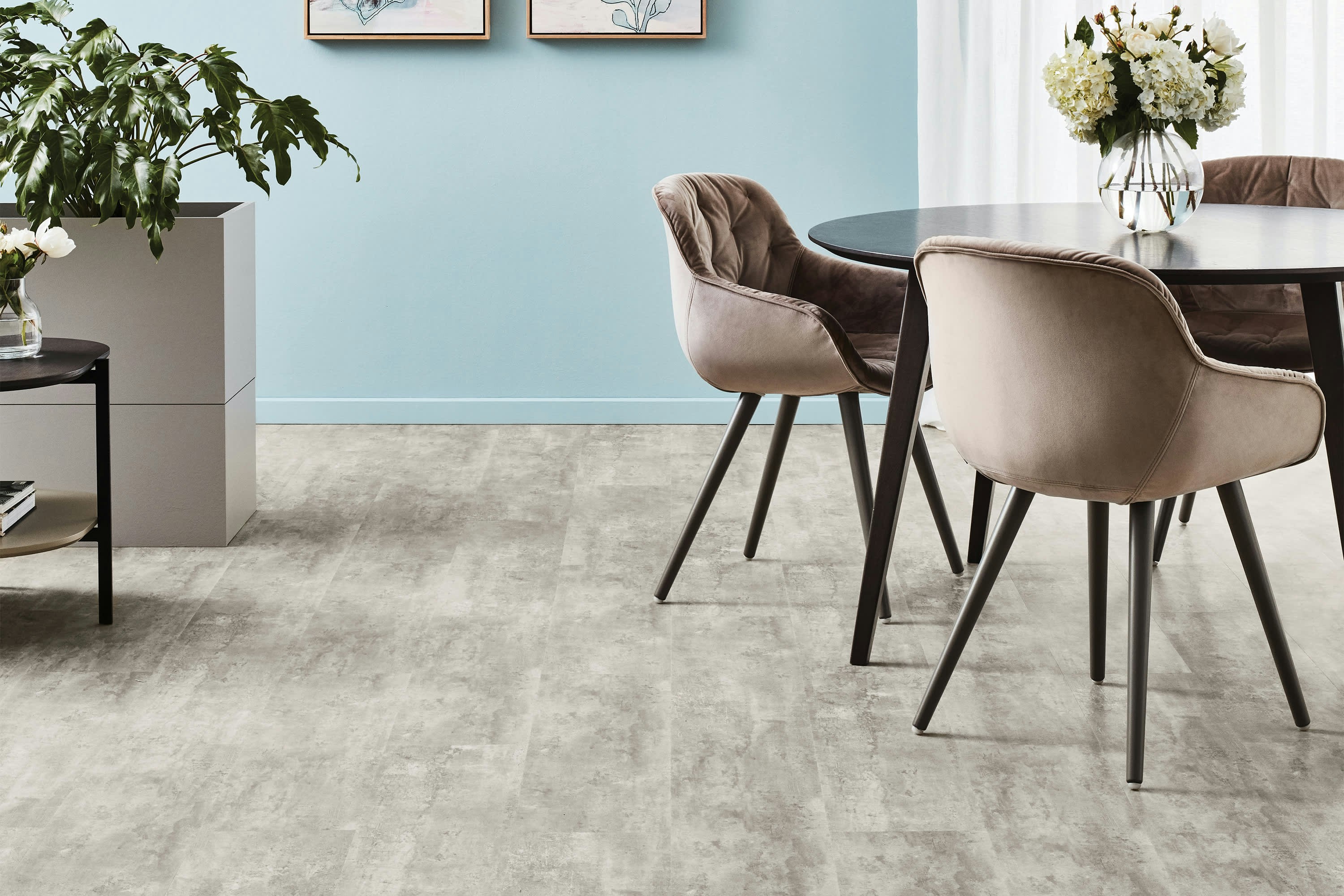 Modern dining room with plush chairs and floral centerpiece.