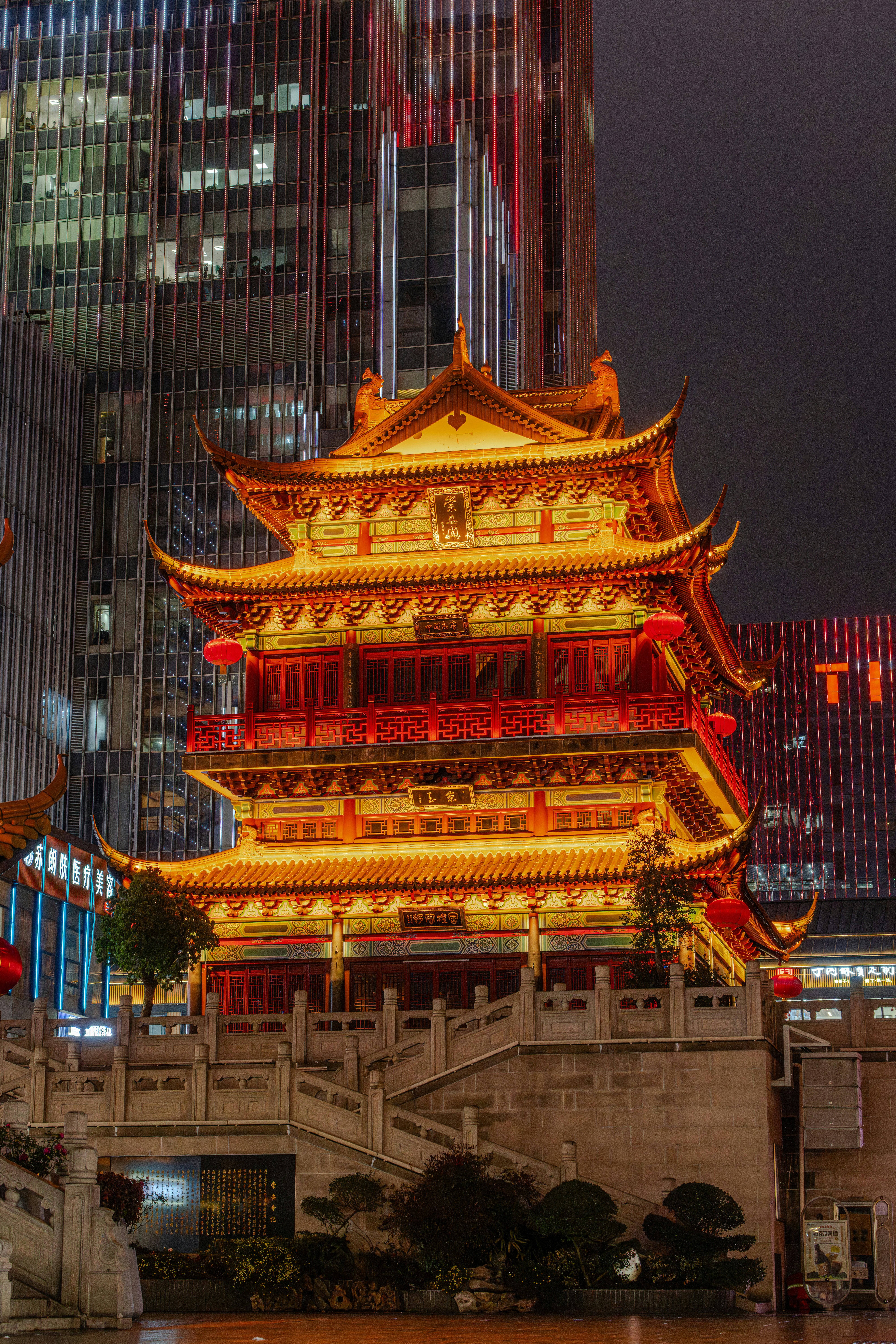 伝統的なパゴダ建築は夜に照らされ、現代的な超高層ビルが建っています。
