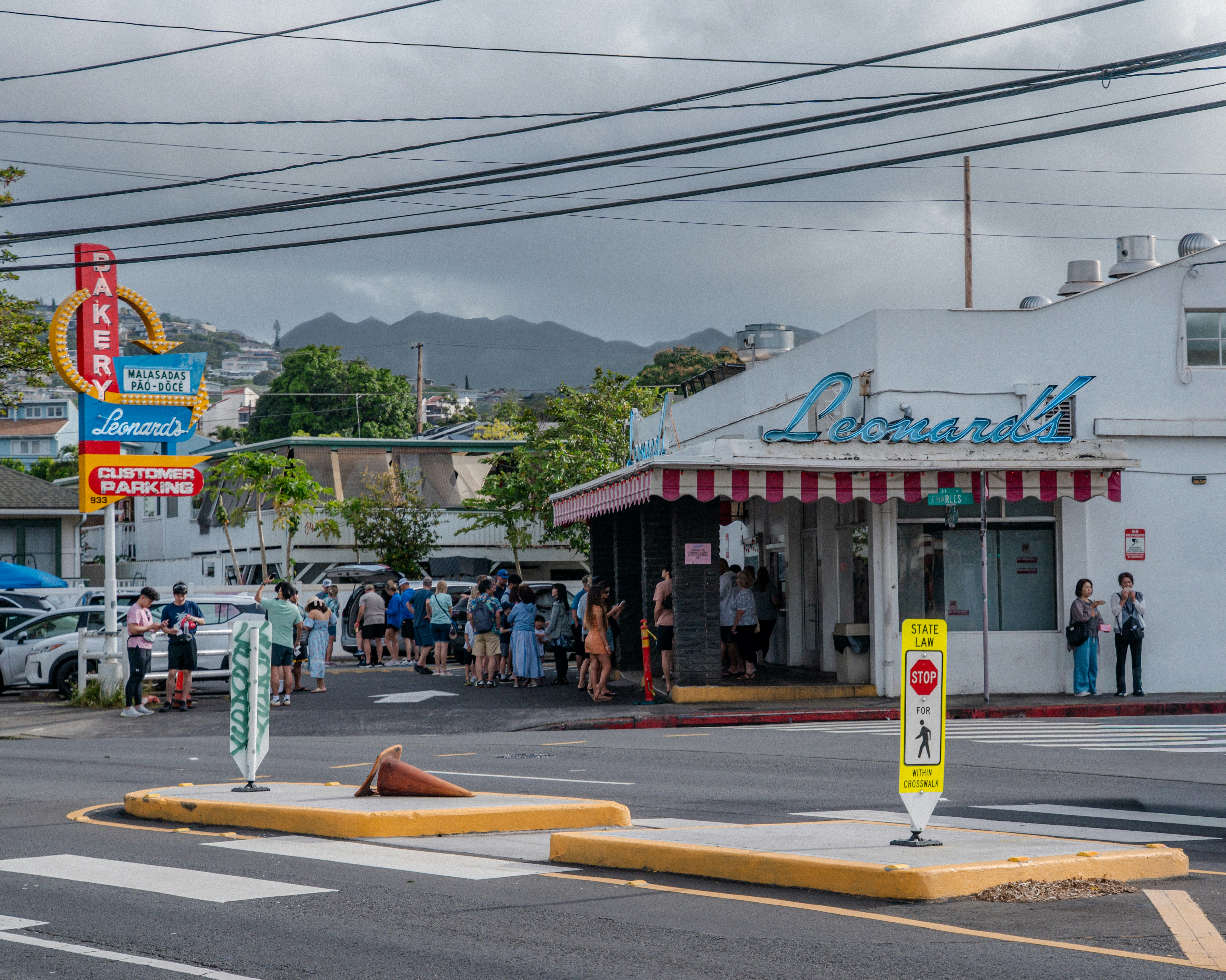 Pessoas na fila do lado de fora de uma loja com uma placa retrô