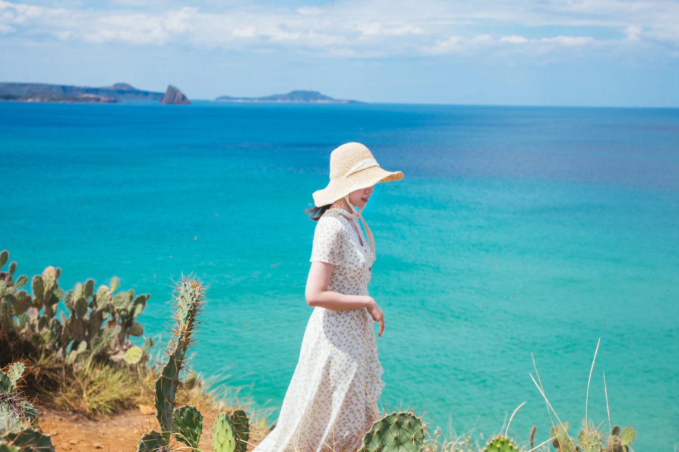 Woman in a flowing white linen dress walking on a tropical beach