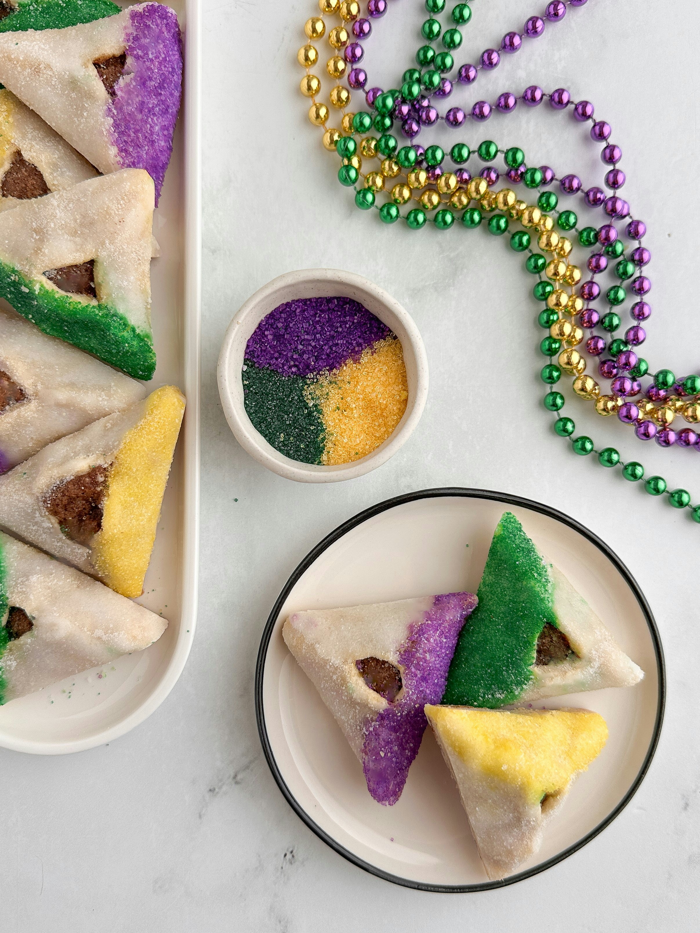Triangular cookies decorated with purple, green, and yellow sugar