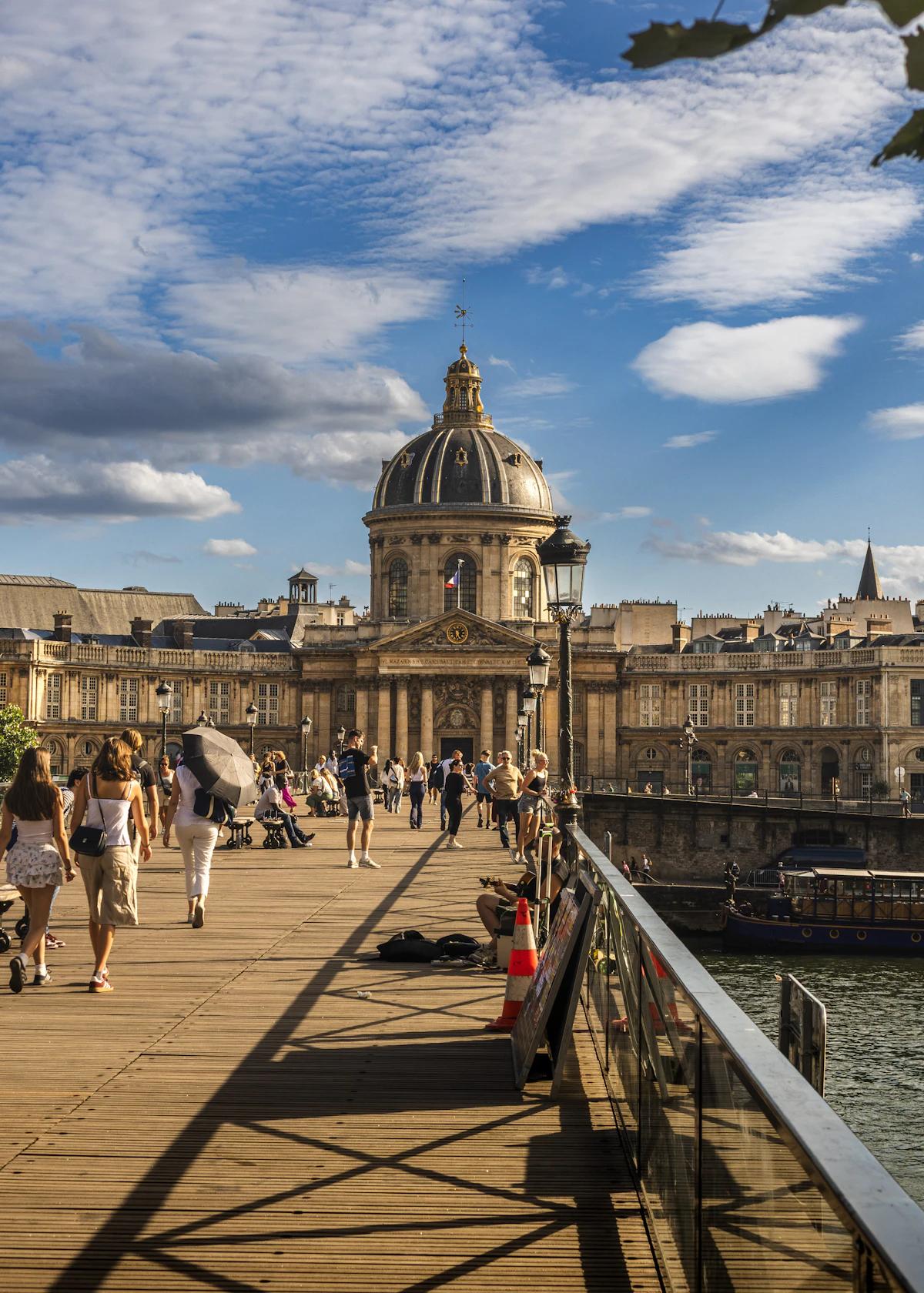 People crossing the Pont des Arts toward the Institut de France in late-afternoon light