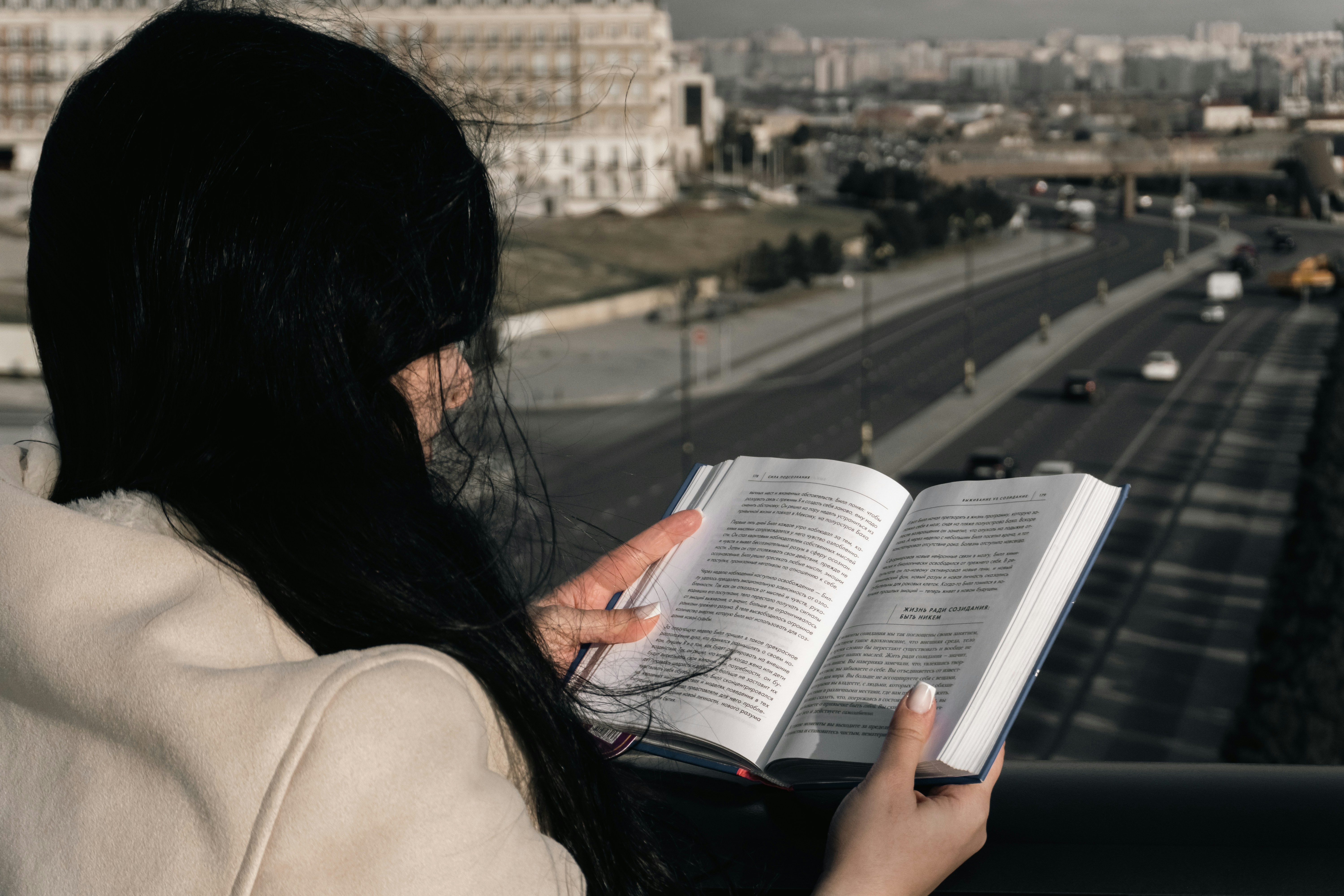 Woman reading a book overlooking a city street