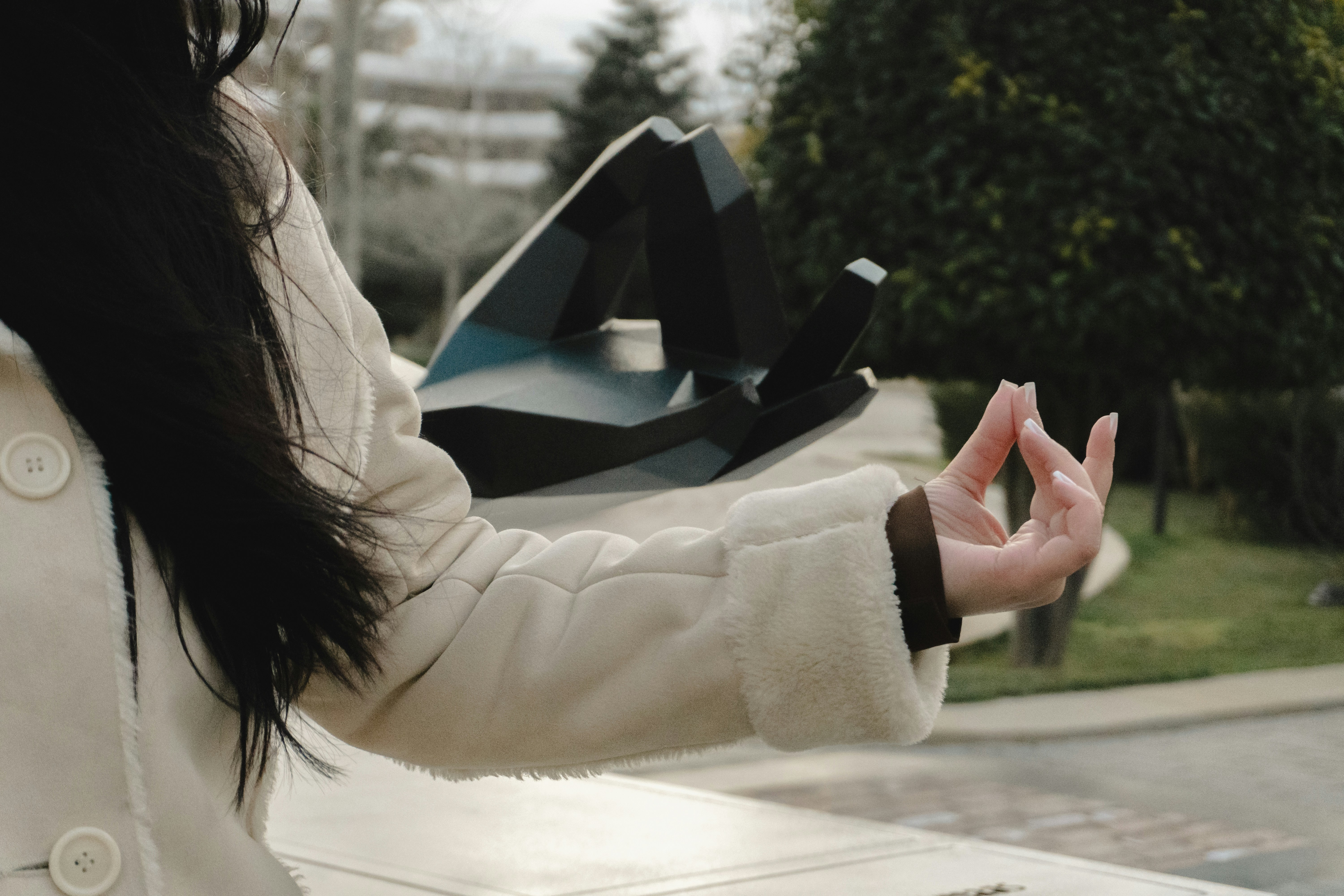 A person holding a geometric object in a park.