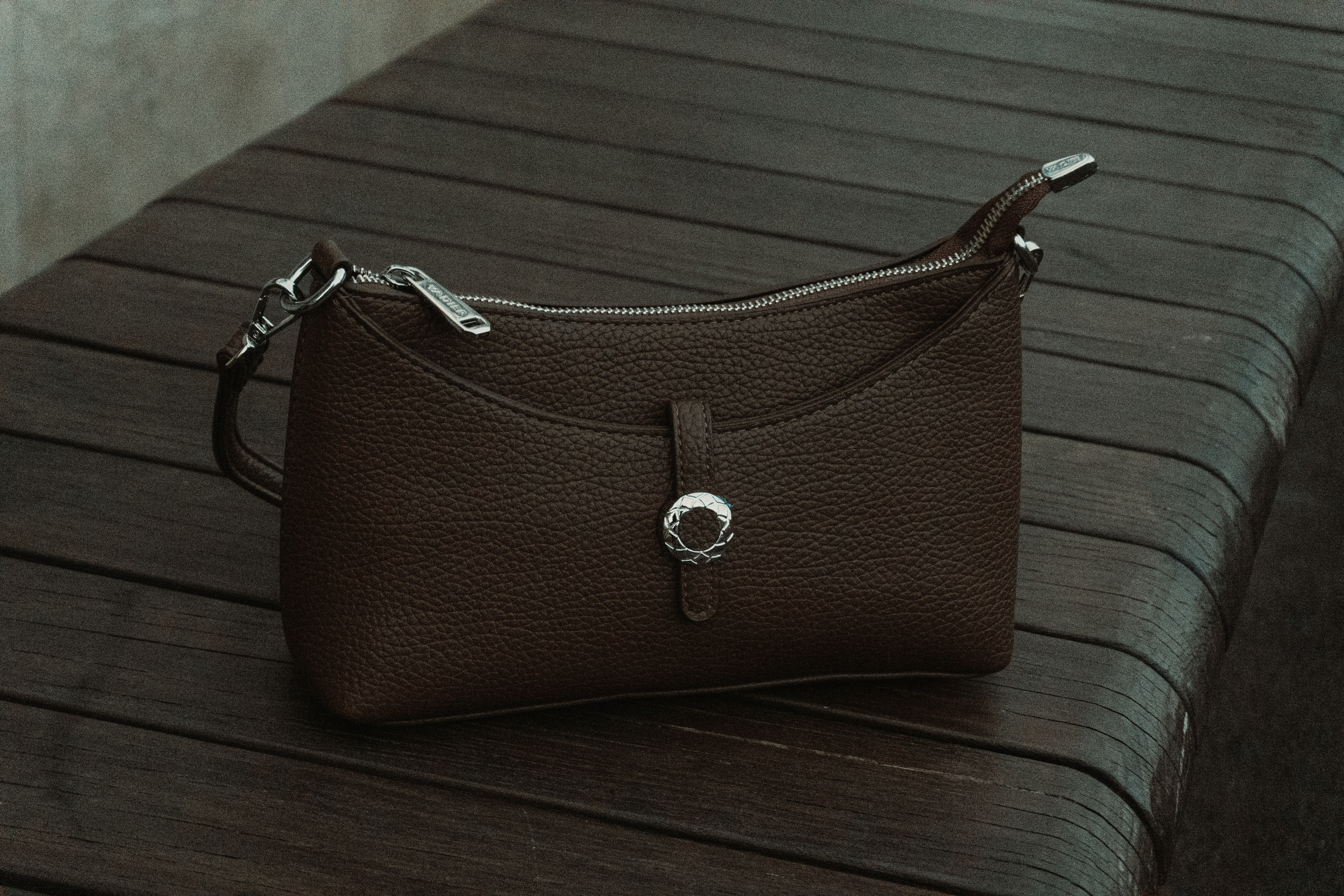 A brown leather handbag rests on a wooden surface.