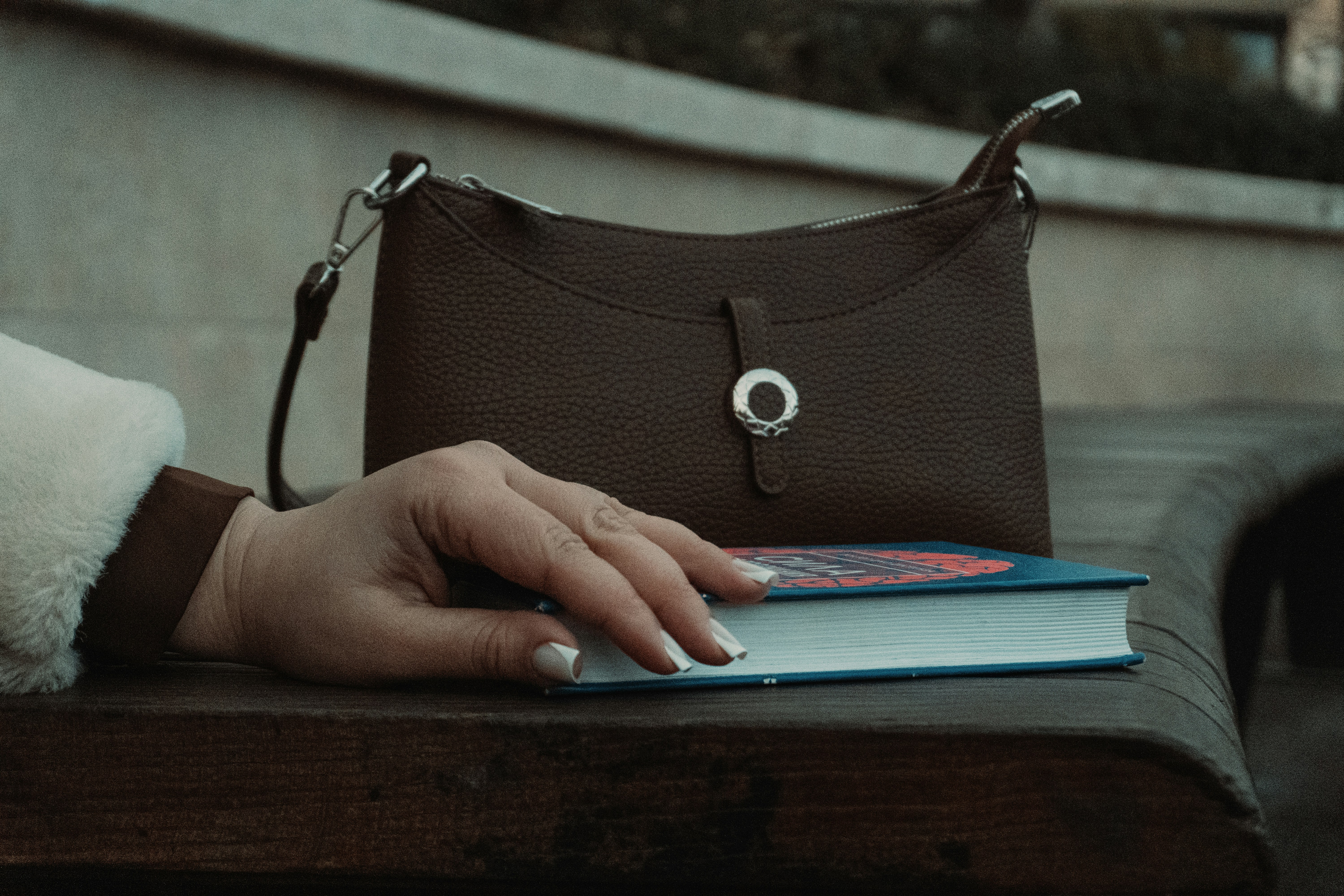 A brown handbag rests on a book.
