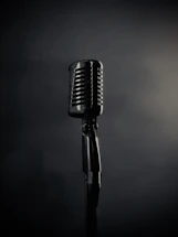 A vintage microphone stands on a dark background