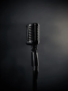 A vintage microphone stands on a dark background