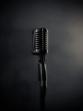 A vintage microphone stands on a dark background