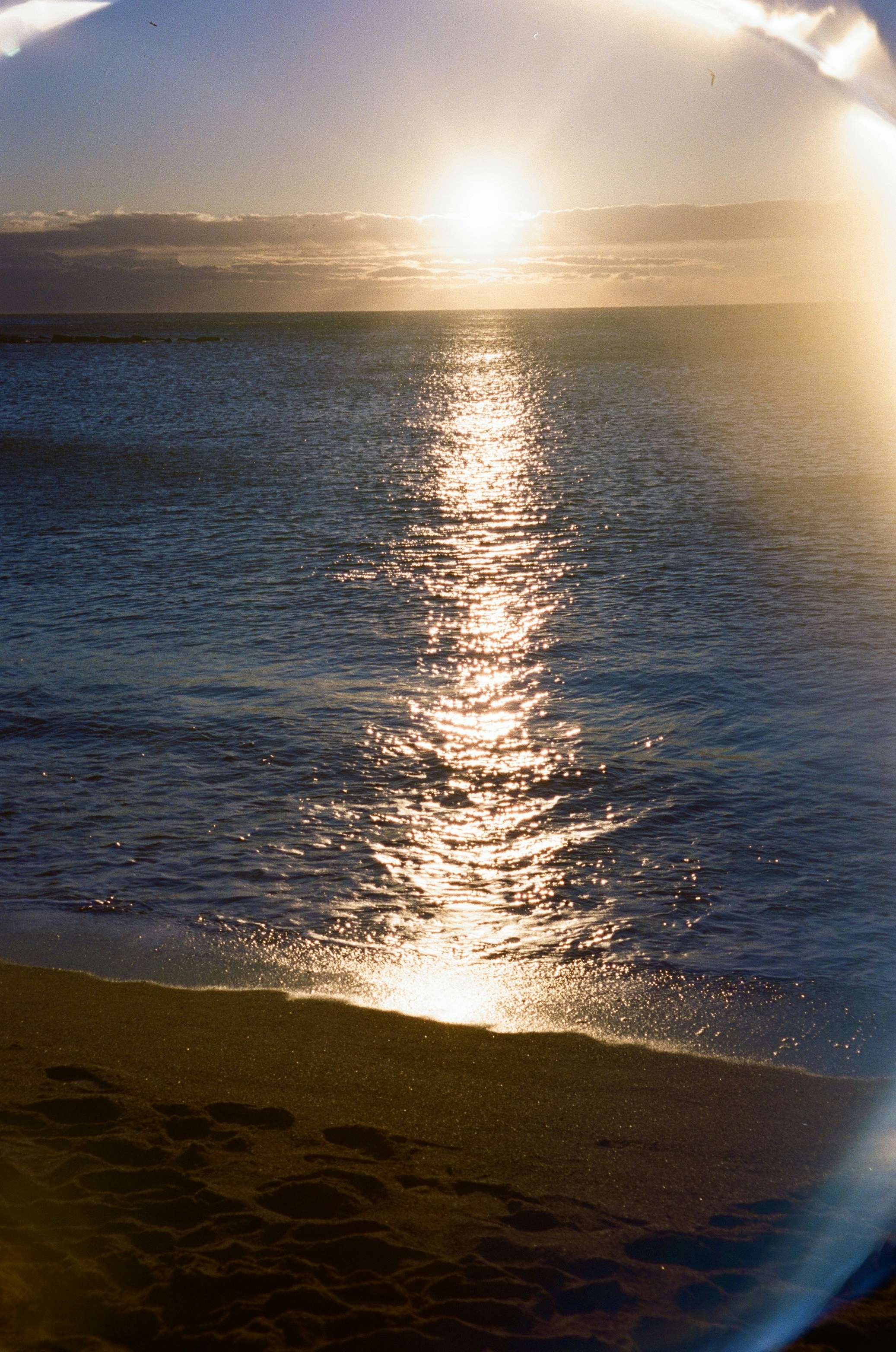 Golden sun reflects on the ocean waves at sunset.