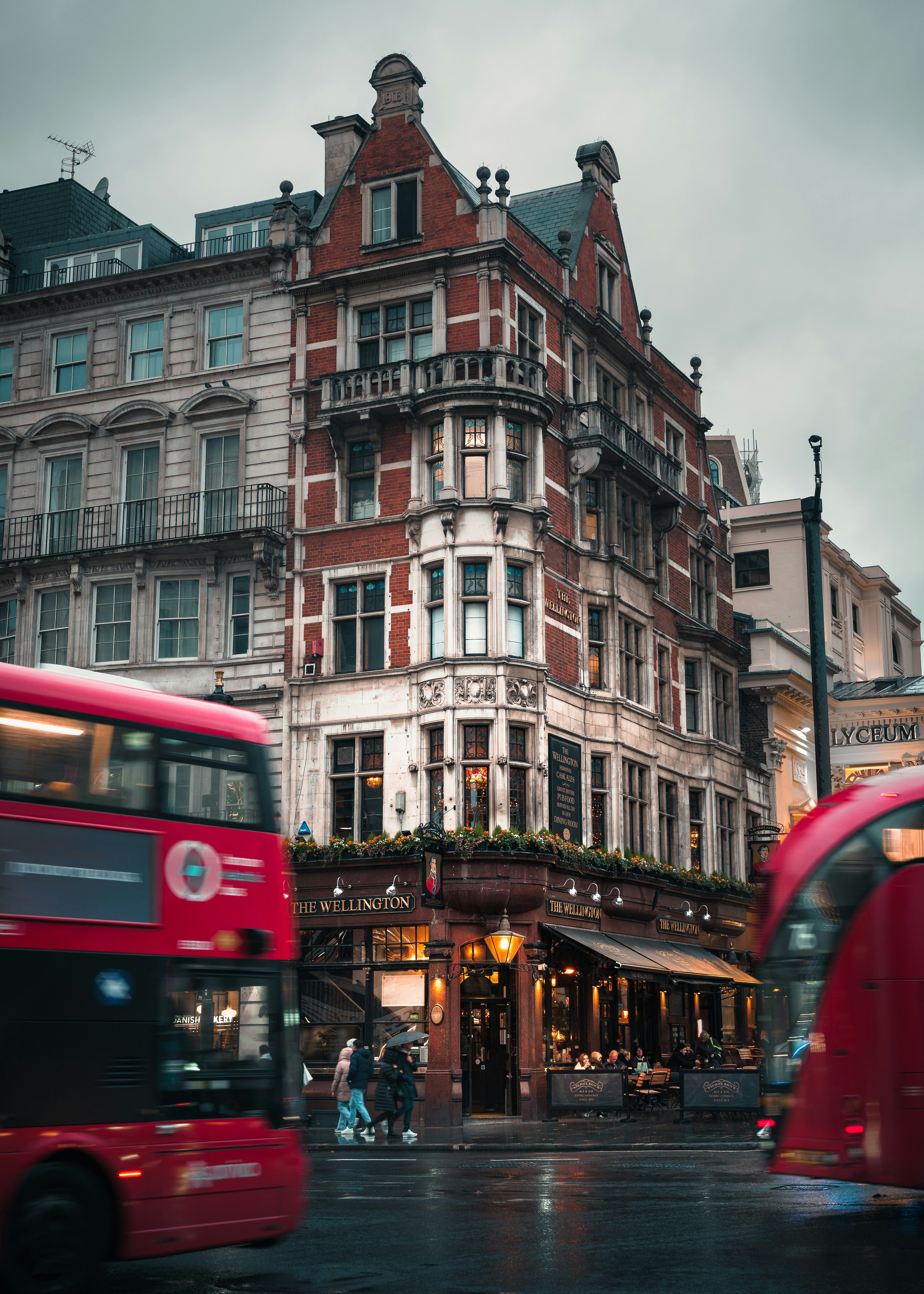 Bus bertingkat merah melewati gedung-gedung bersejarah di London.