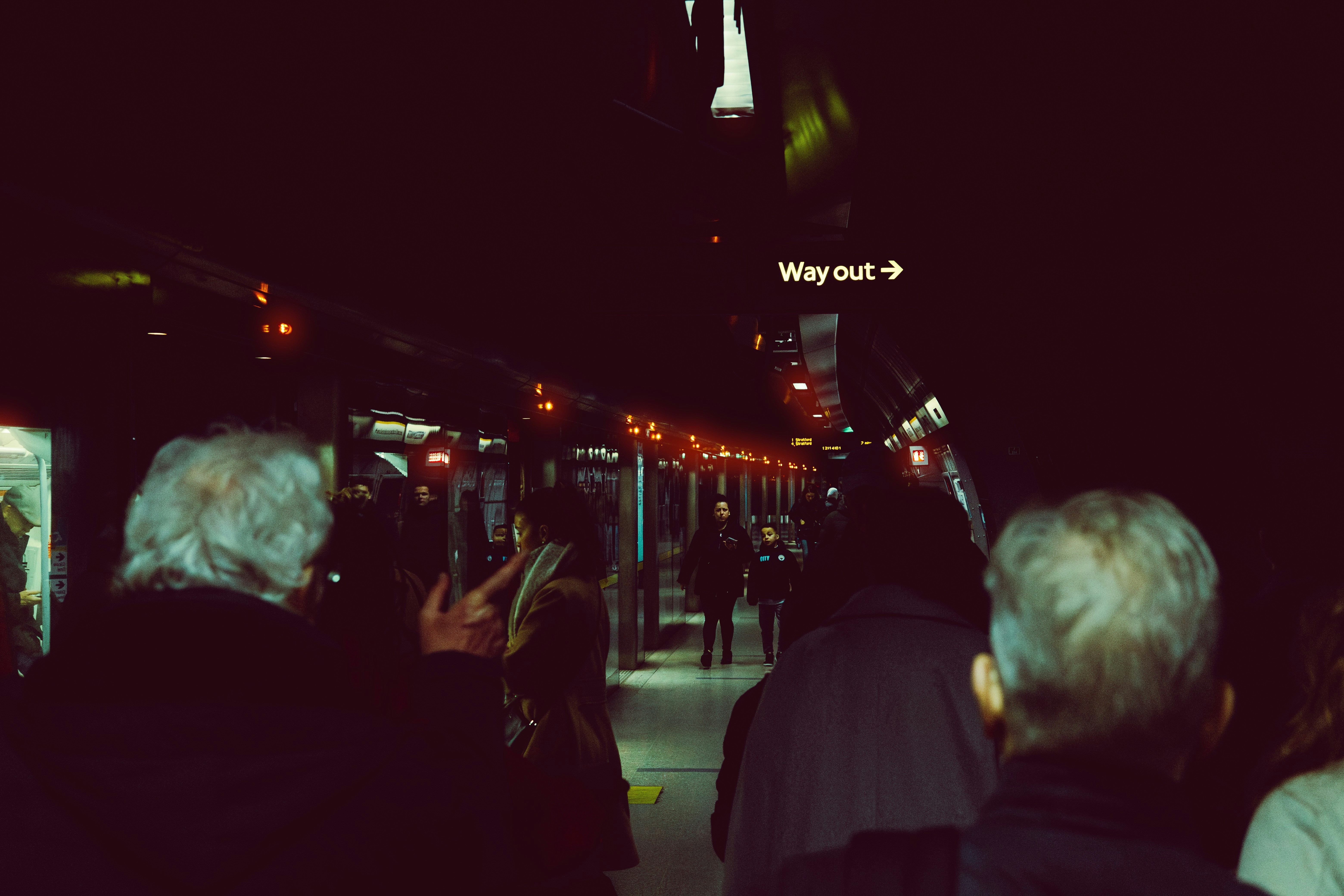 People waiting on a dark train station platform at night.