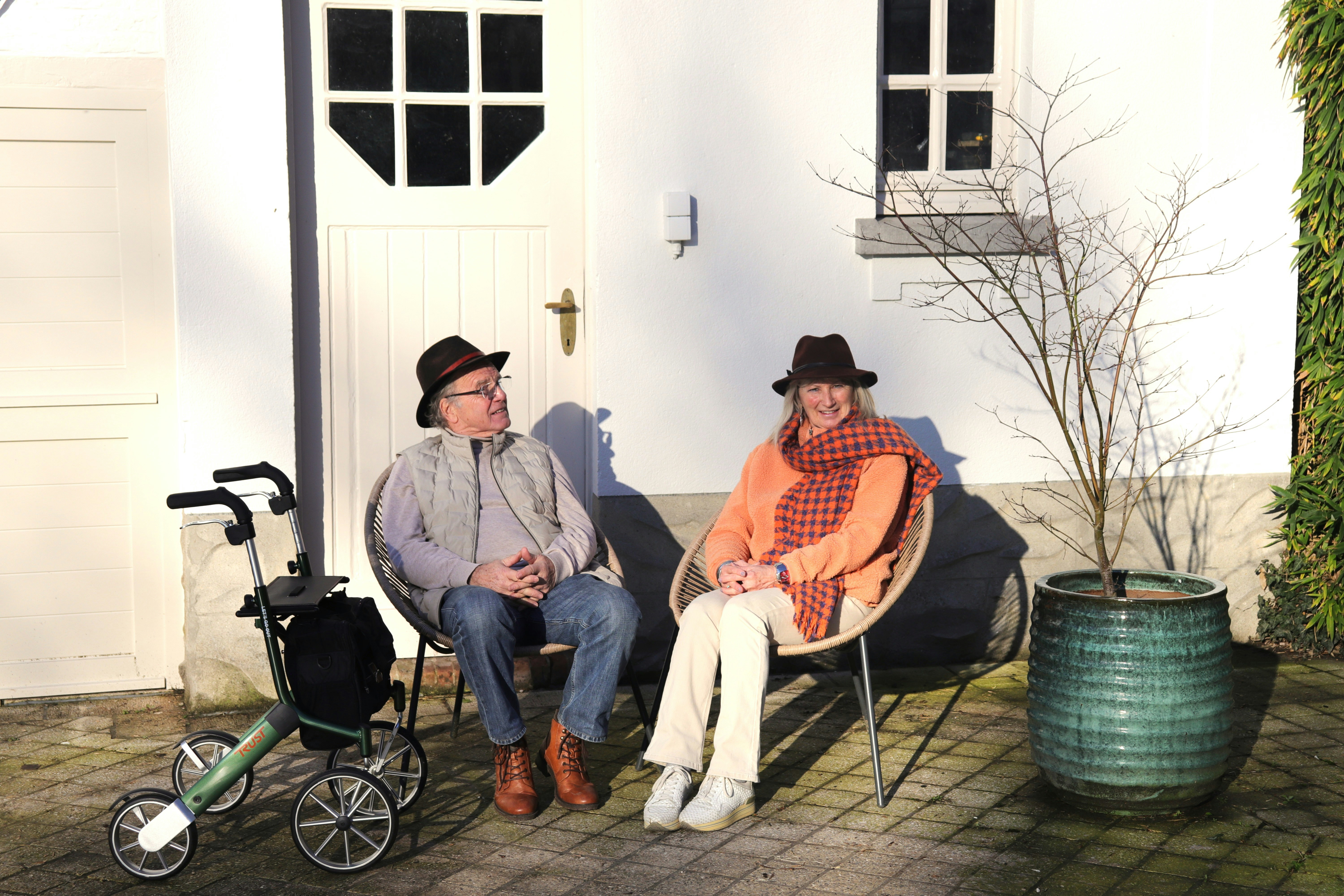 Couple âgé assis dehors avec des chapeaux et un déambulateur