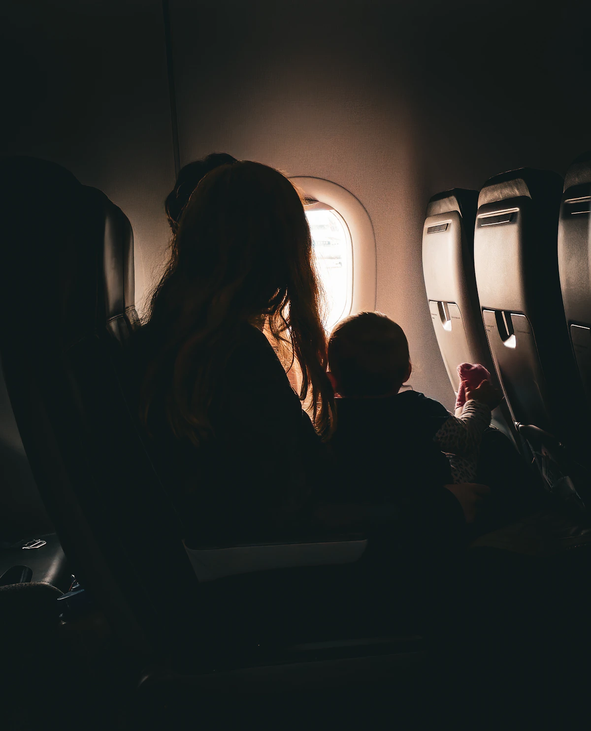 Mother and child looking out airplane window together