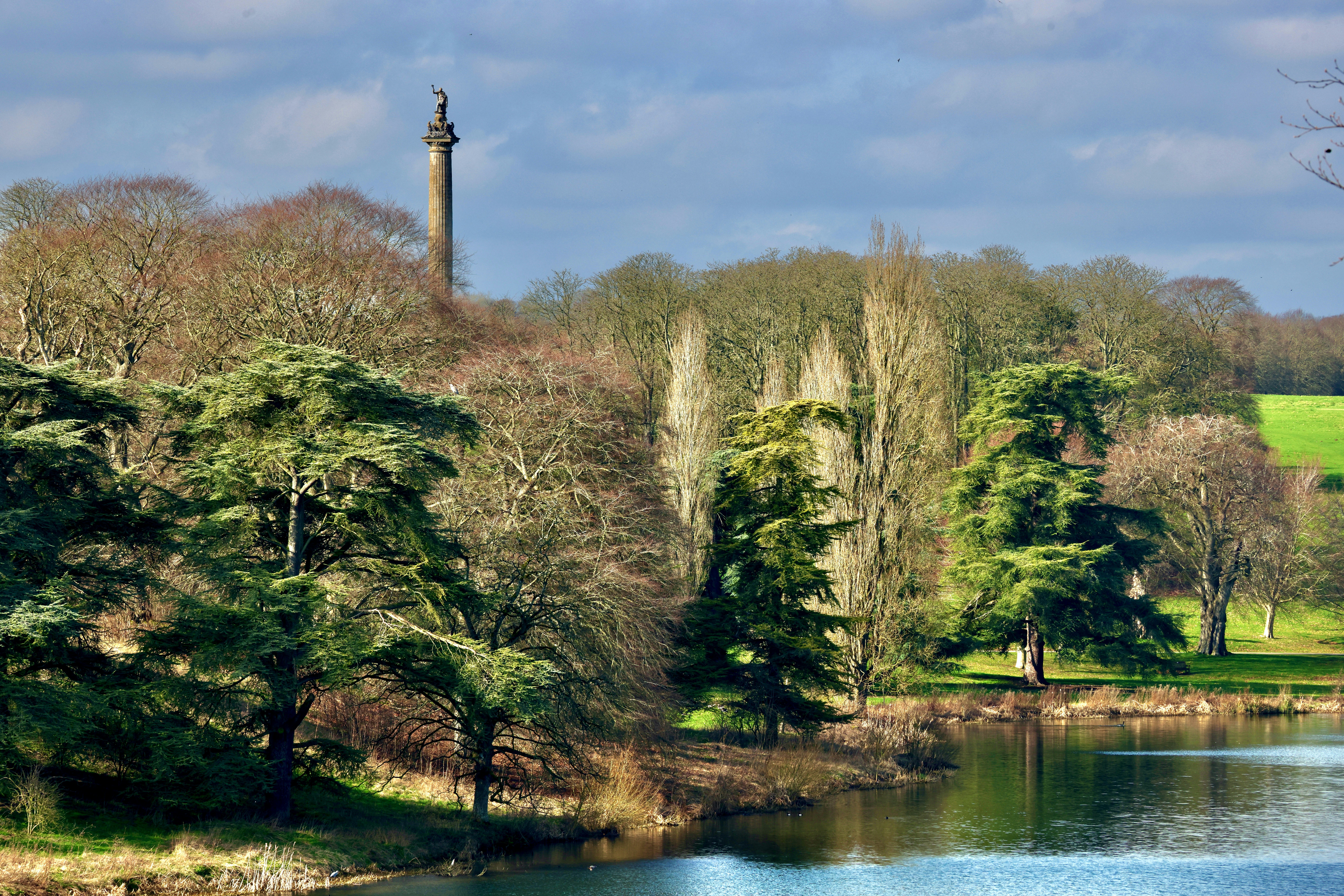 Monument atop a hill overlooking a lake with trees