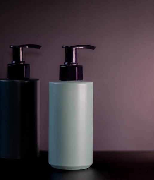 Two pump bottles on a dark shelf