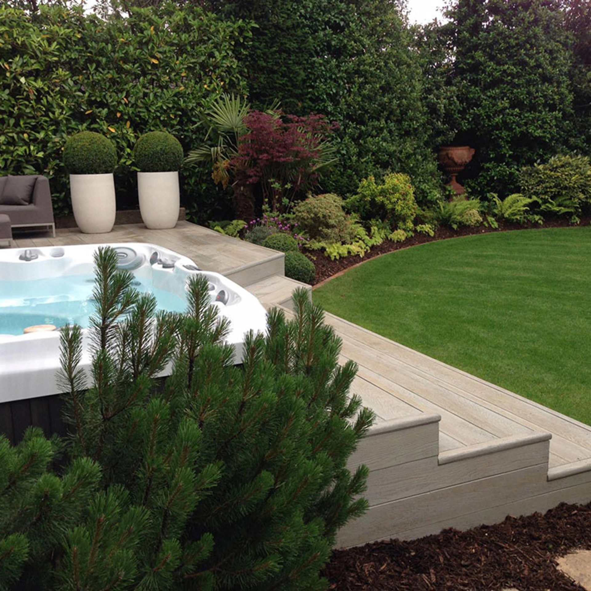 Hot tub on a wooden deck surrounded by lush garden