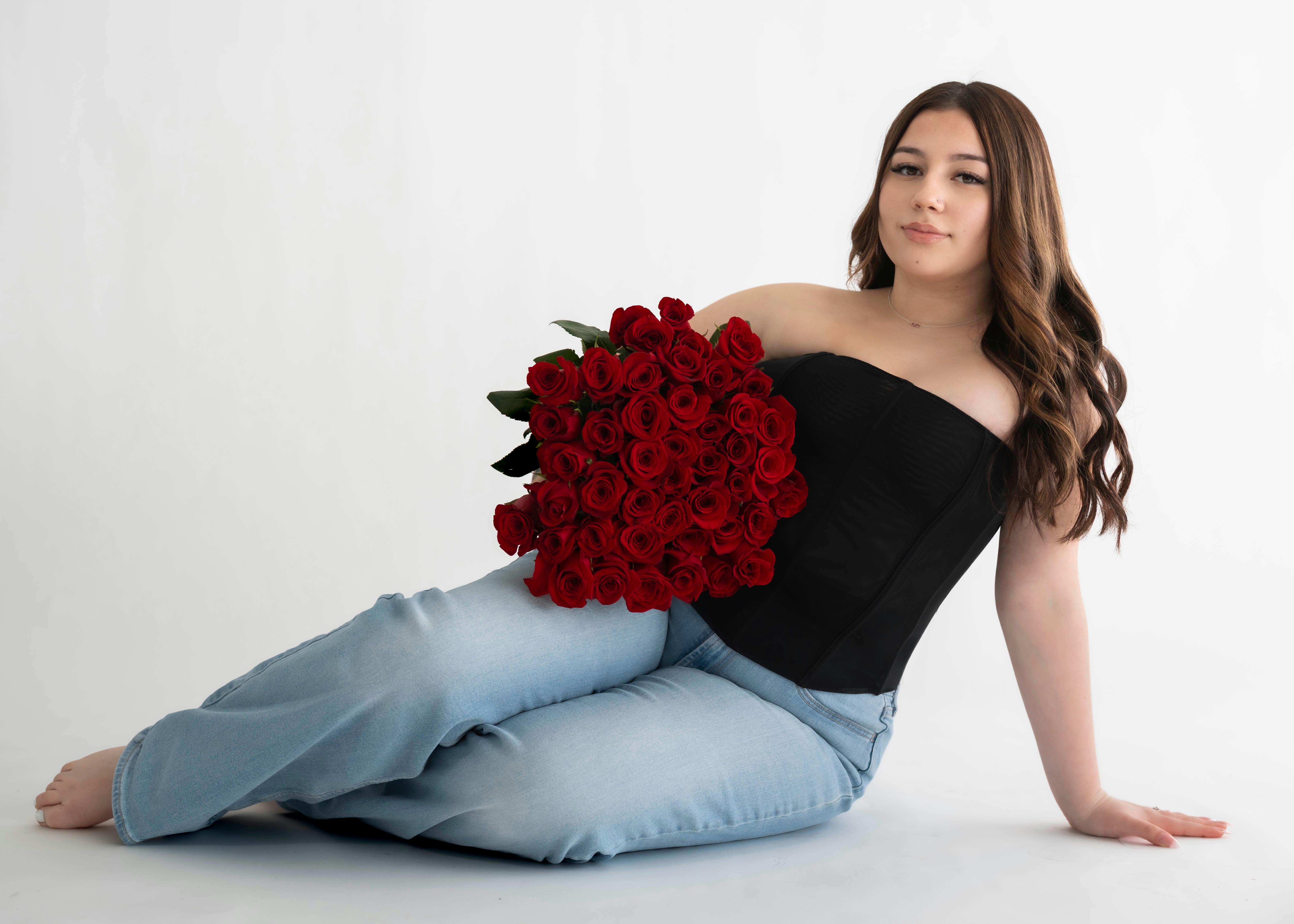 Young woman in jeans holding red roses