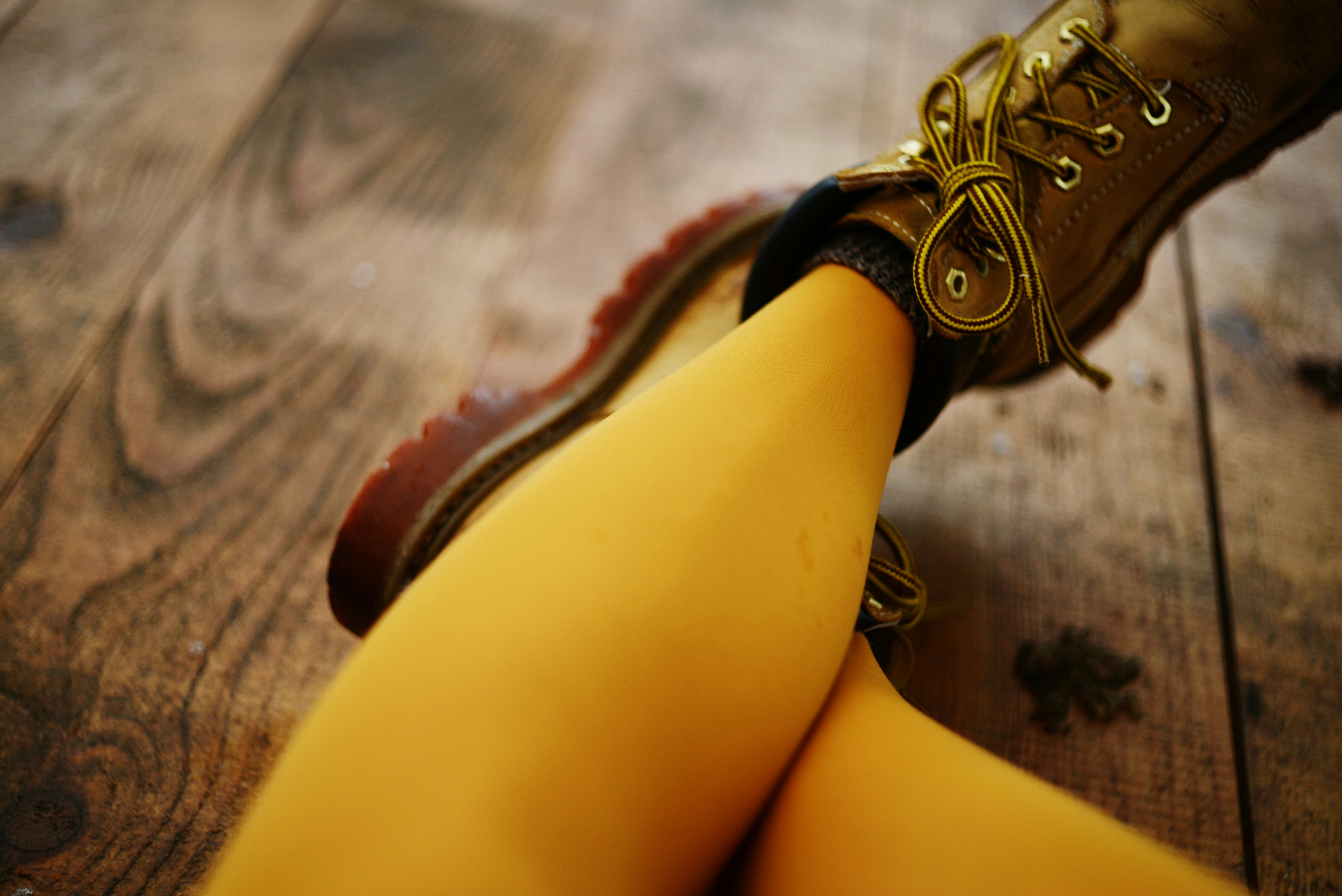 Las piernas de una persona con botas color beige sobre un suelo de madera