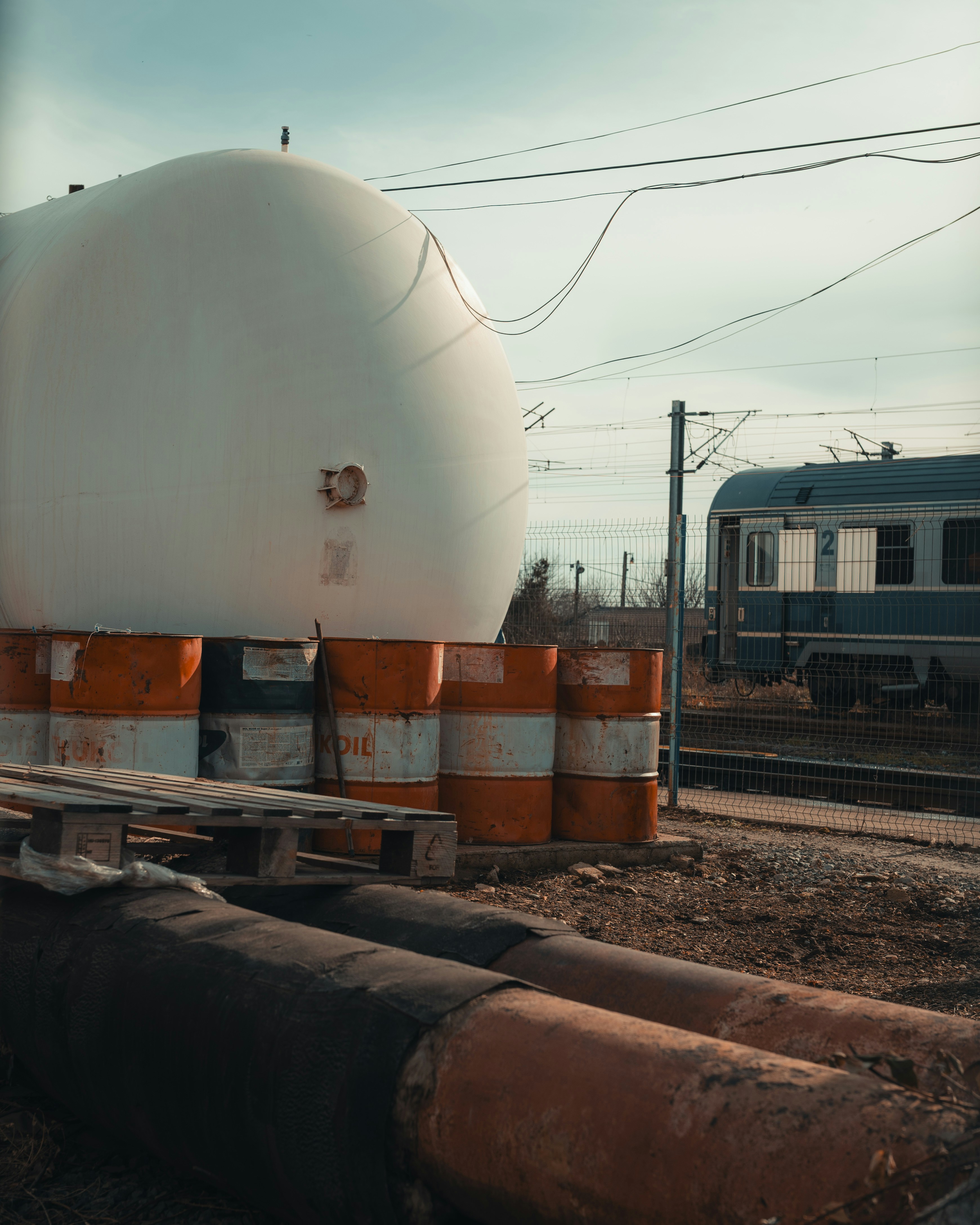 Large white tank with barrels and train