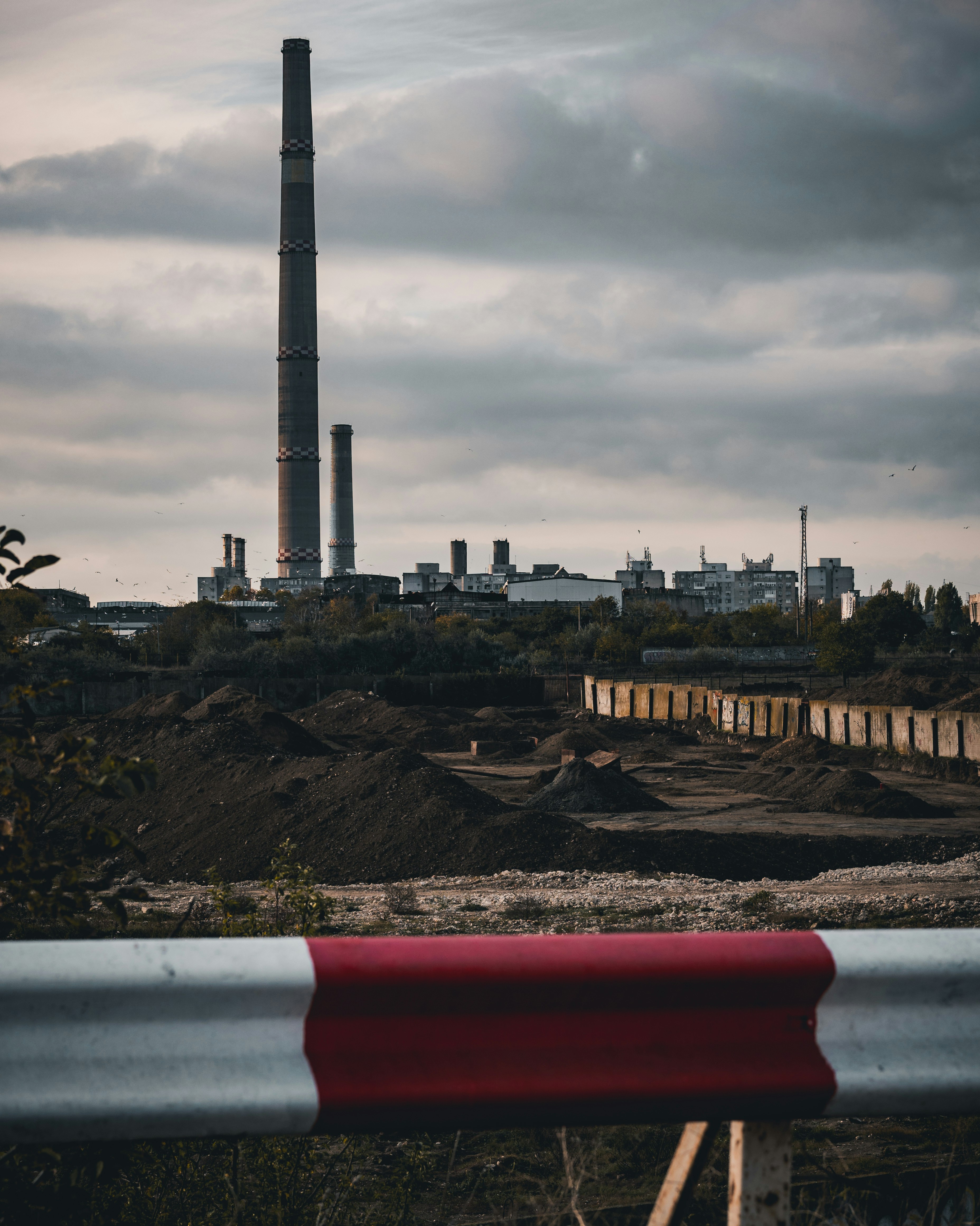 Industrial complex with tall smokestacks under cloudy sky