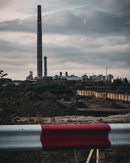 Industrial complex with tall smokestacks under cloudy sky