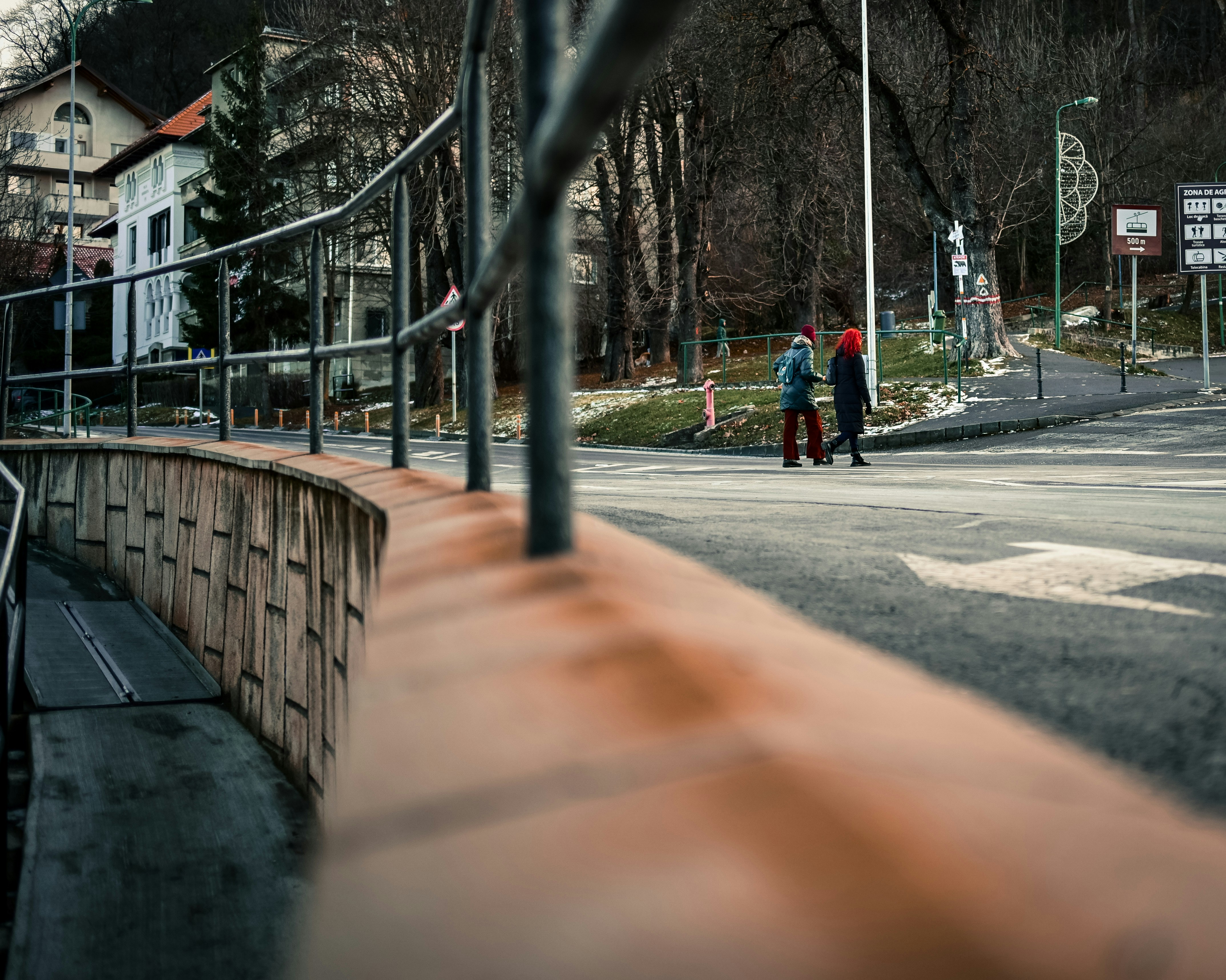 Two children wearing winter hats walk on a street.