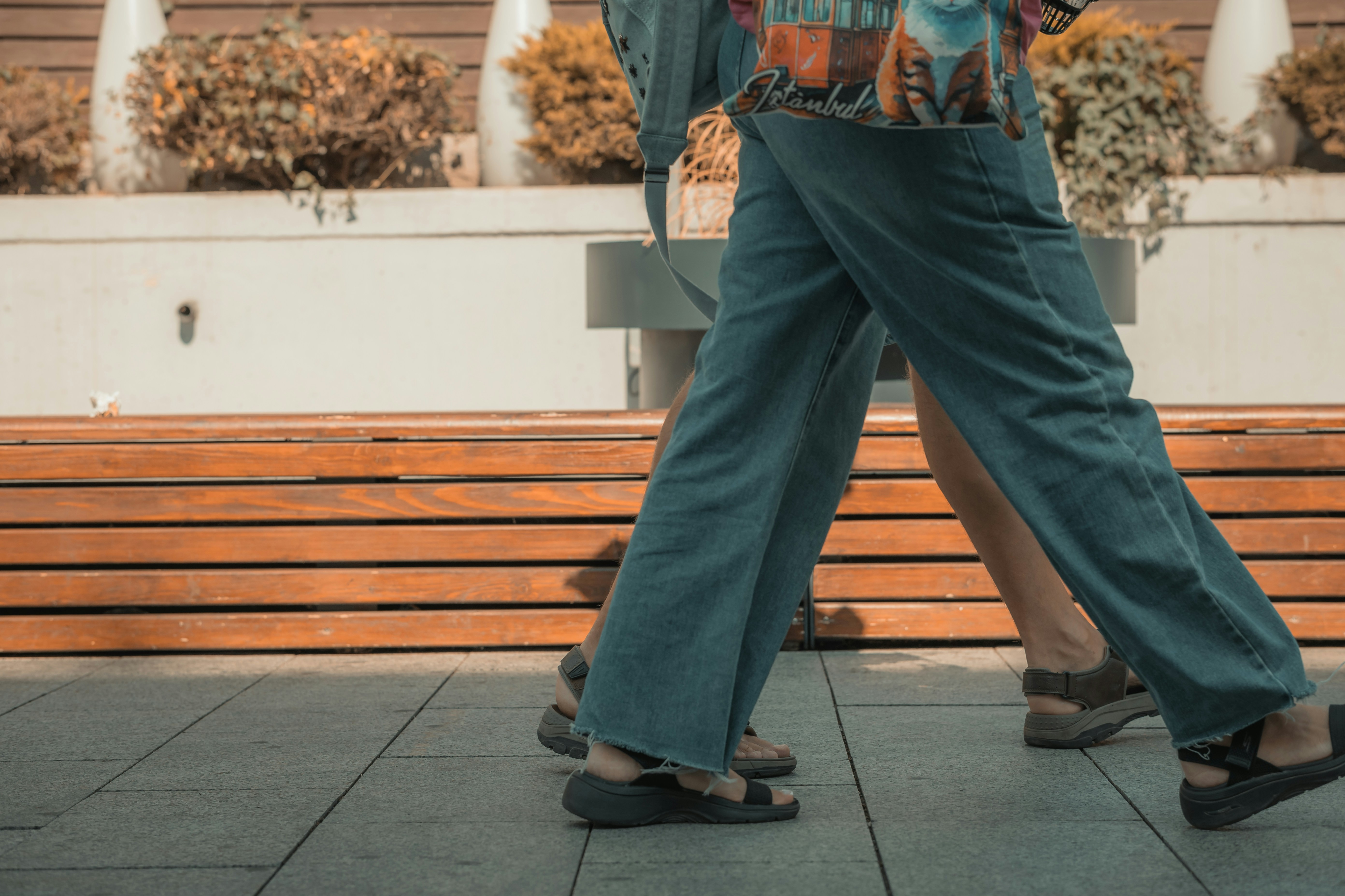 Two people walking on a sidewalk