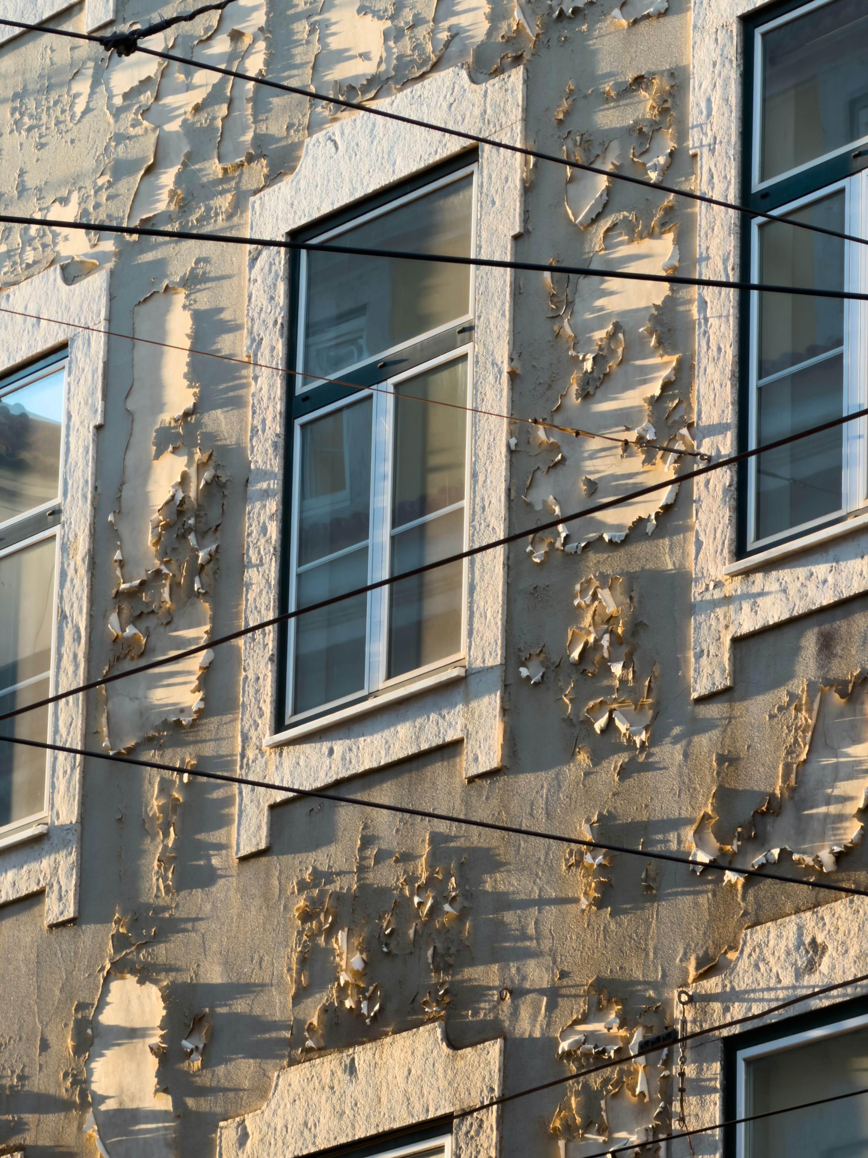 Abblätternde Farbe an einer Gebäudefassade mit Fenstern