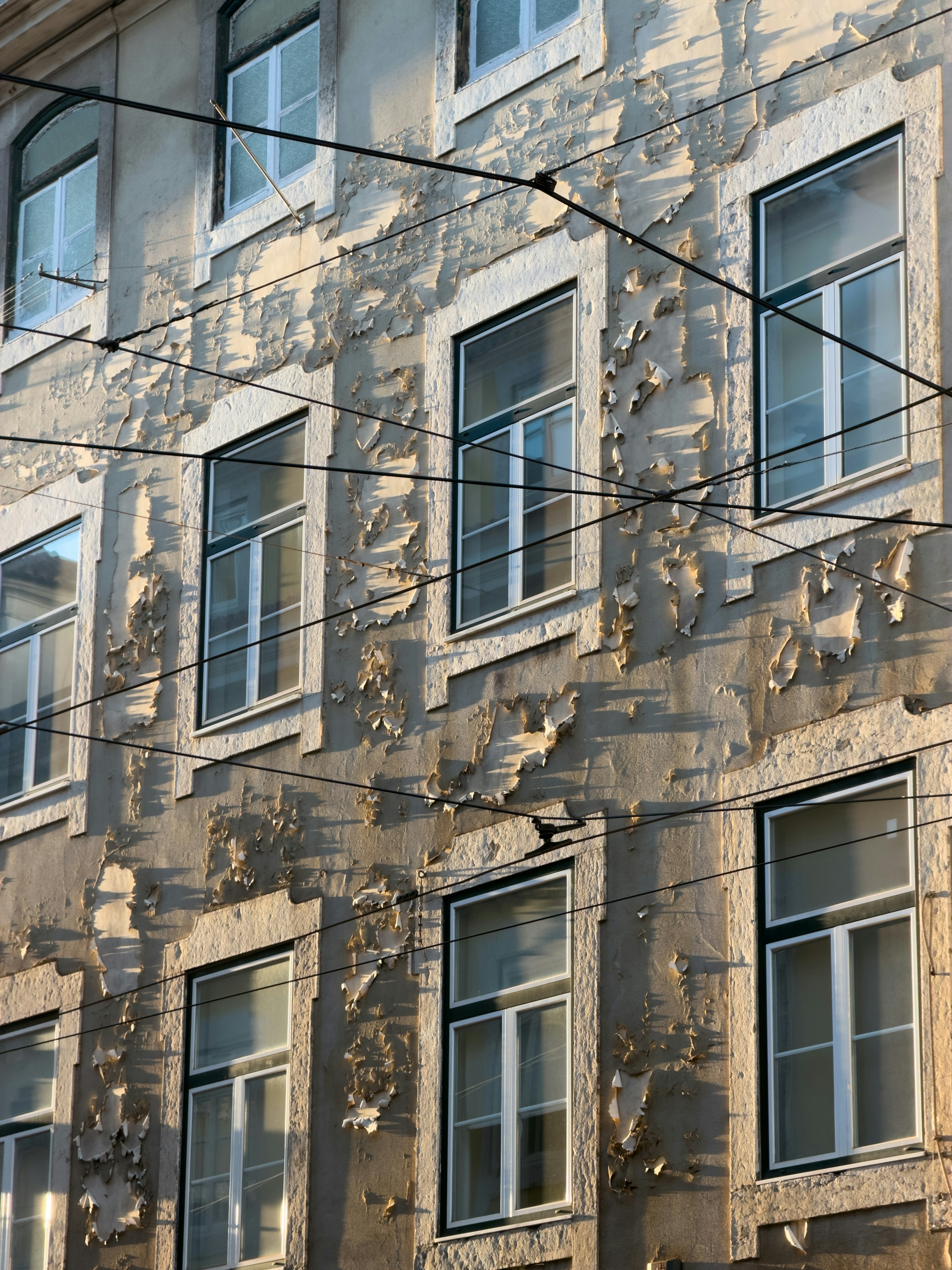 Eine verwitterte Gebäudefassade mit abblätternder Farbe und Fenstern.