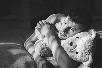 Man hugging a teddy bear on a bed
