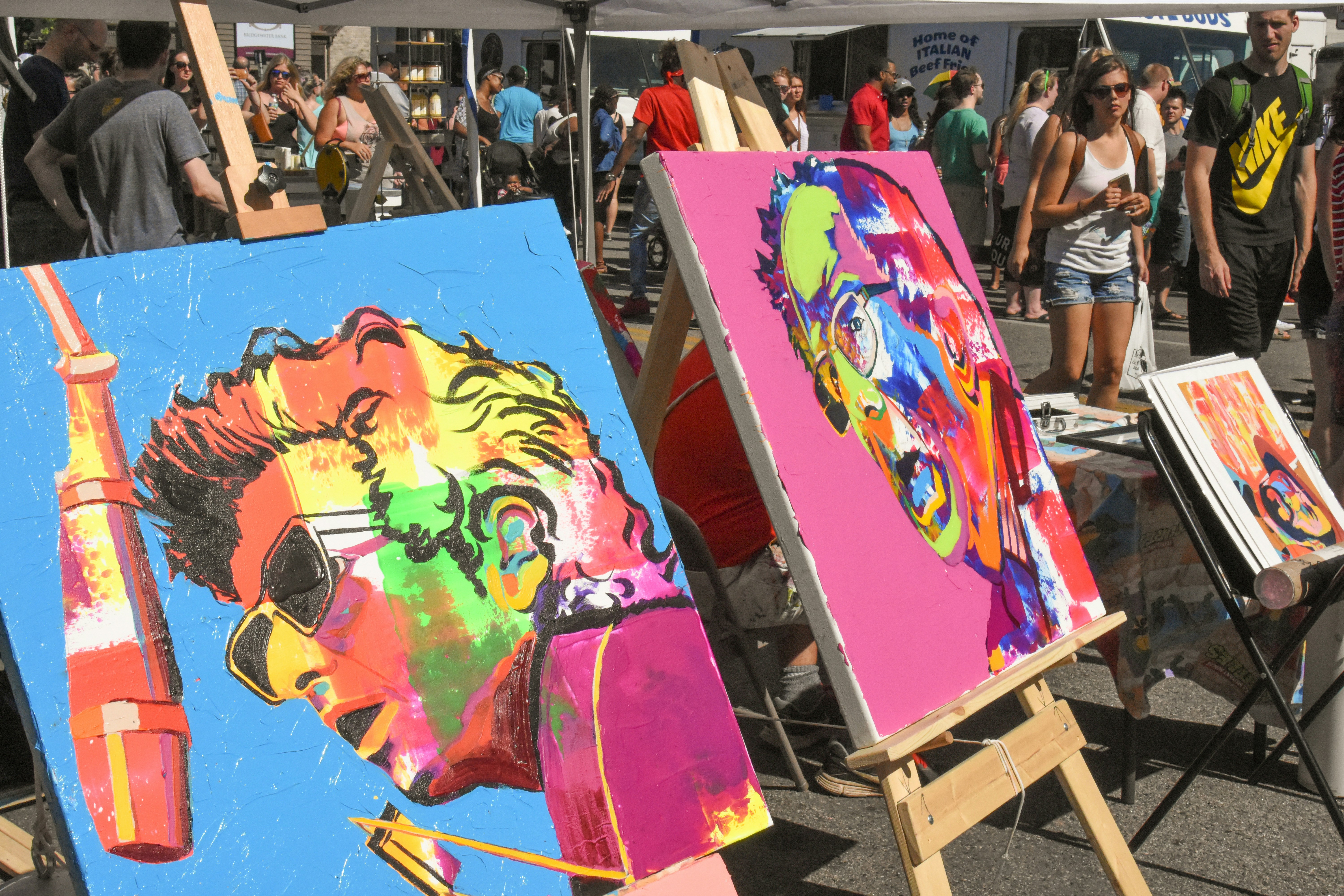 Colorful abstract portraits displayed at an outdoor art fair.