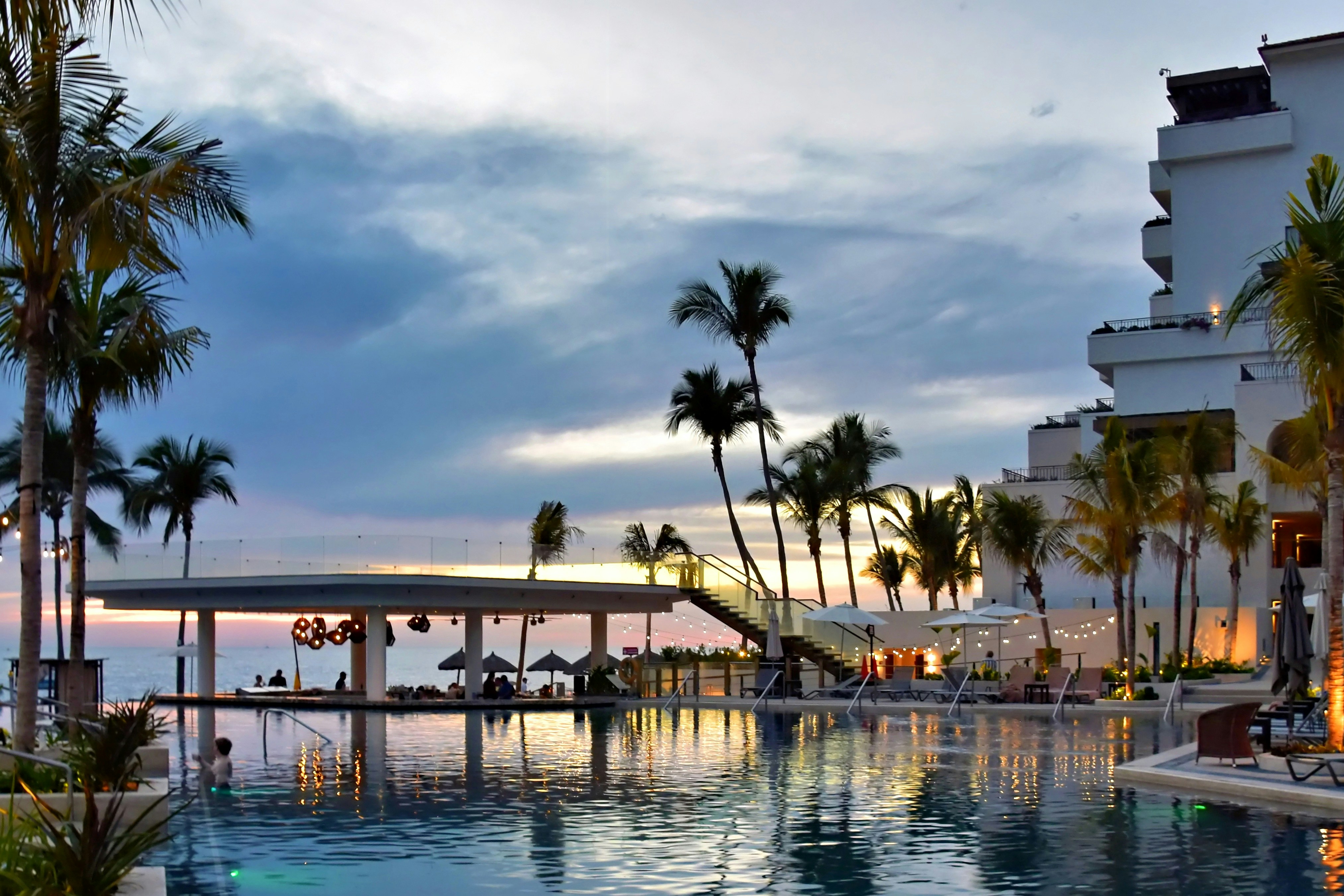 Resort pool and palm trees at sunset
