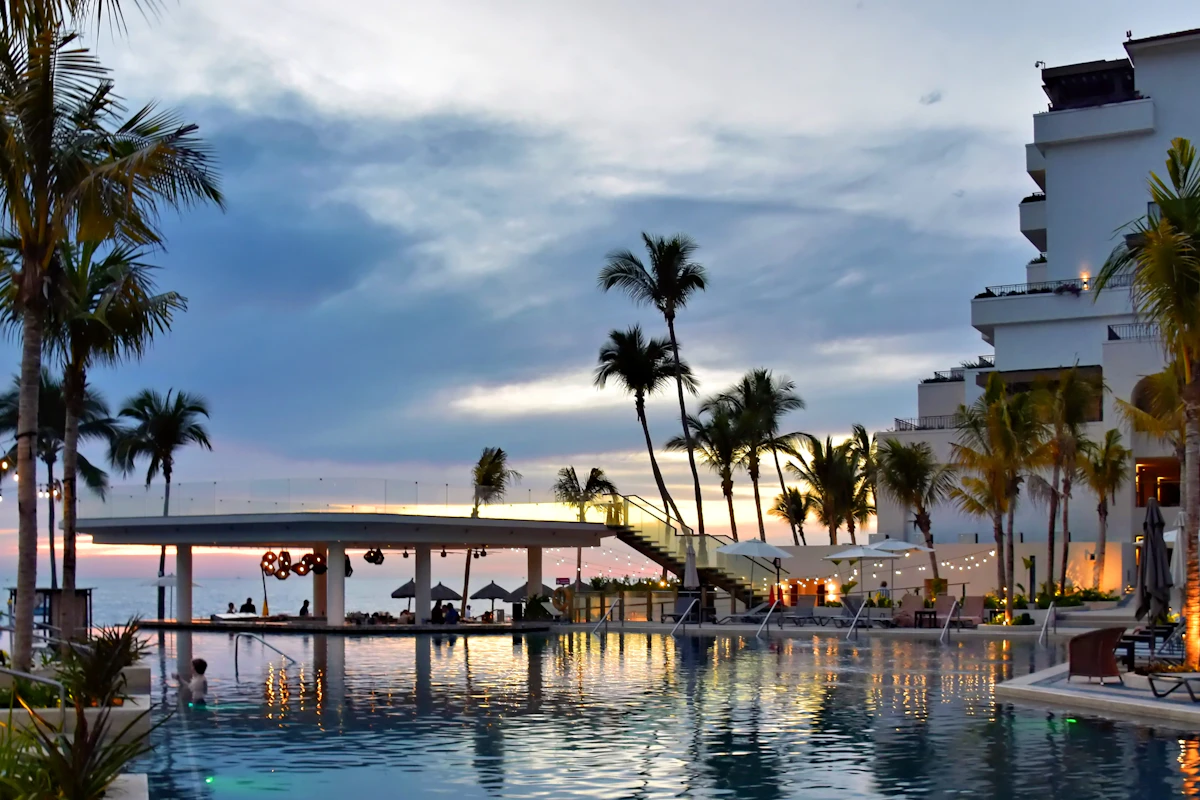 A resort pool with palm trees at sunset on Barbados' west coast