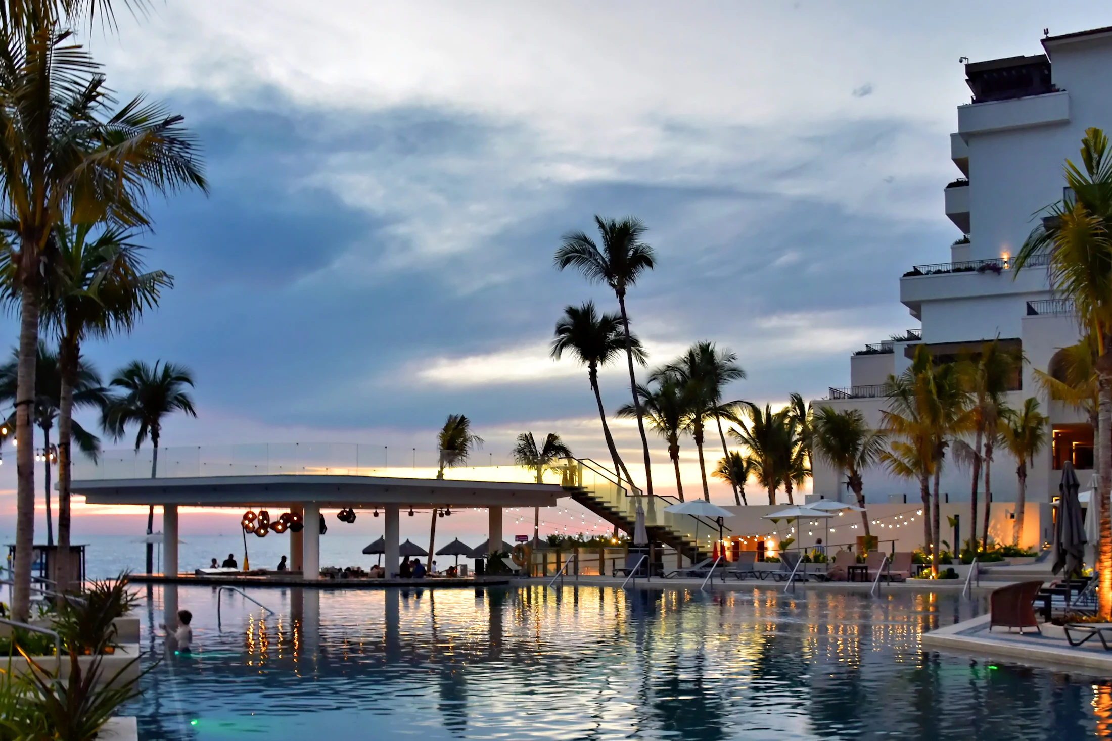 Luxury resort pool and palm trees at sunset