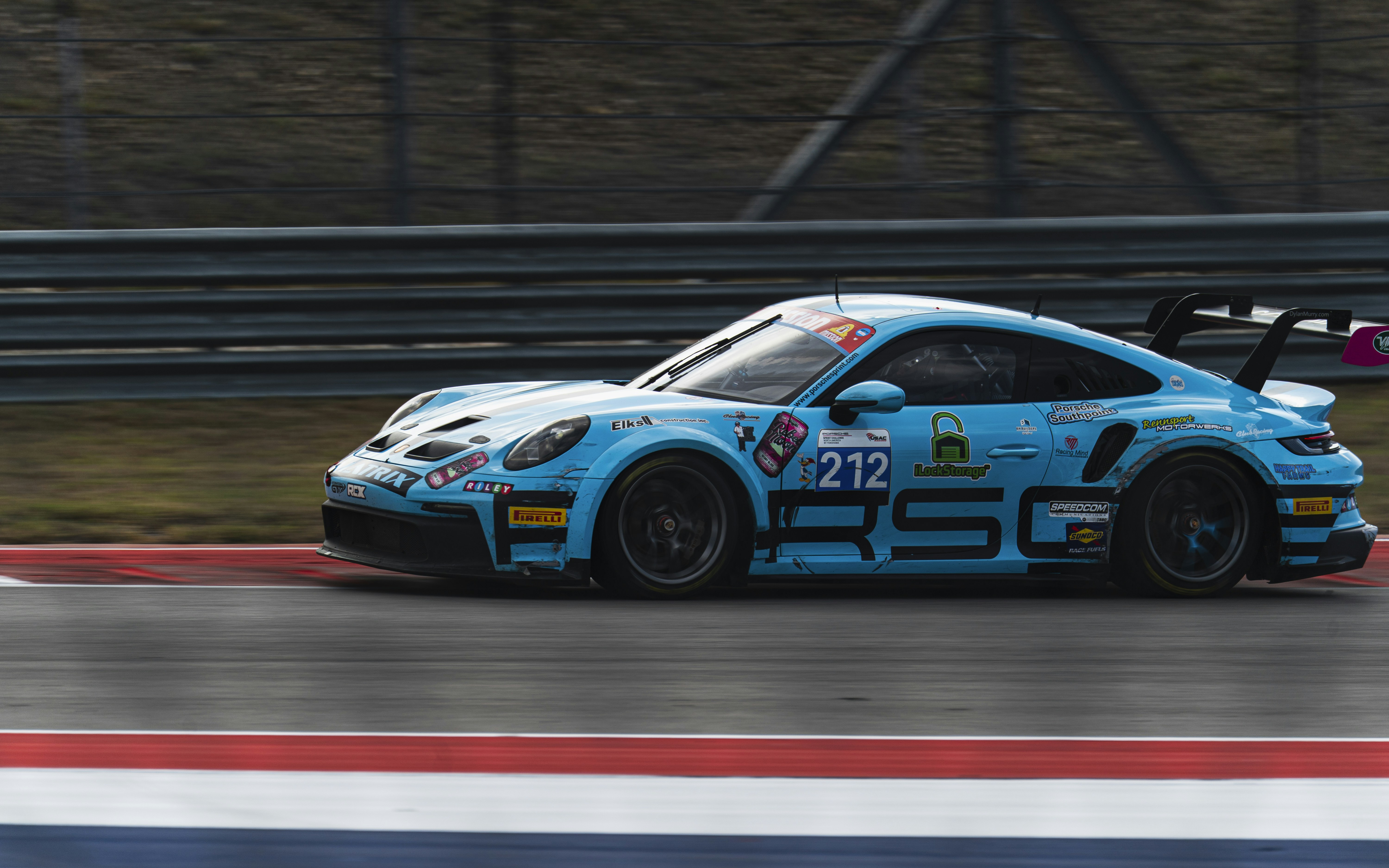 A blue race car speeds down a wet track.