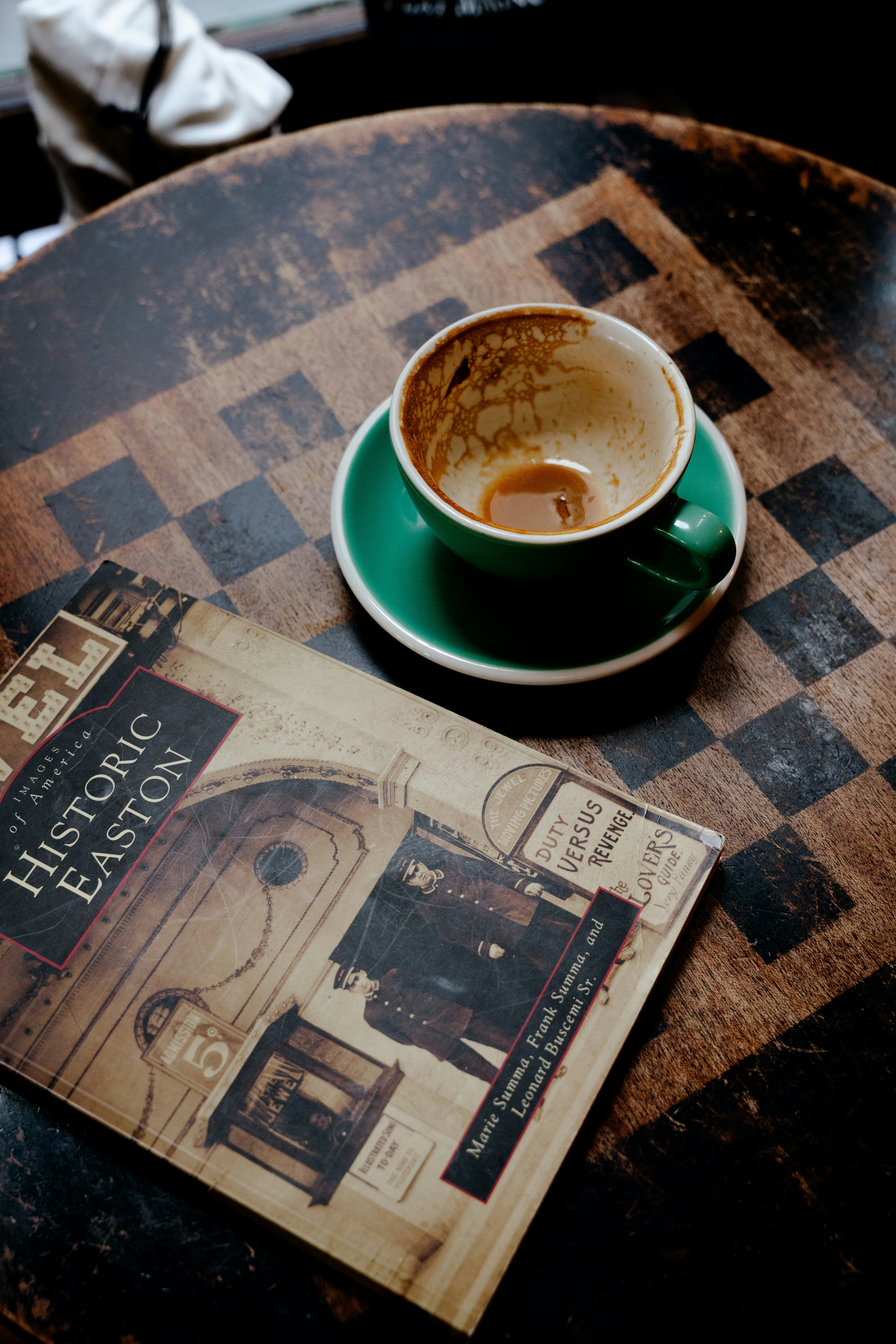 Taza de café vacía y libro sobre una mesa de cuadros