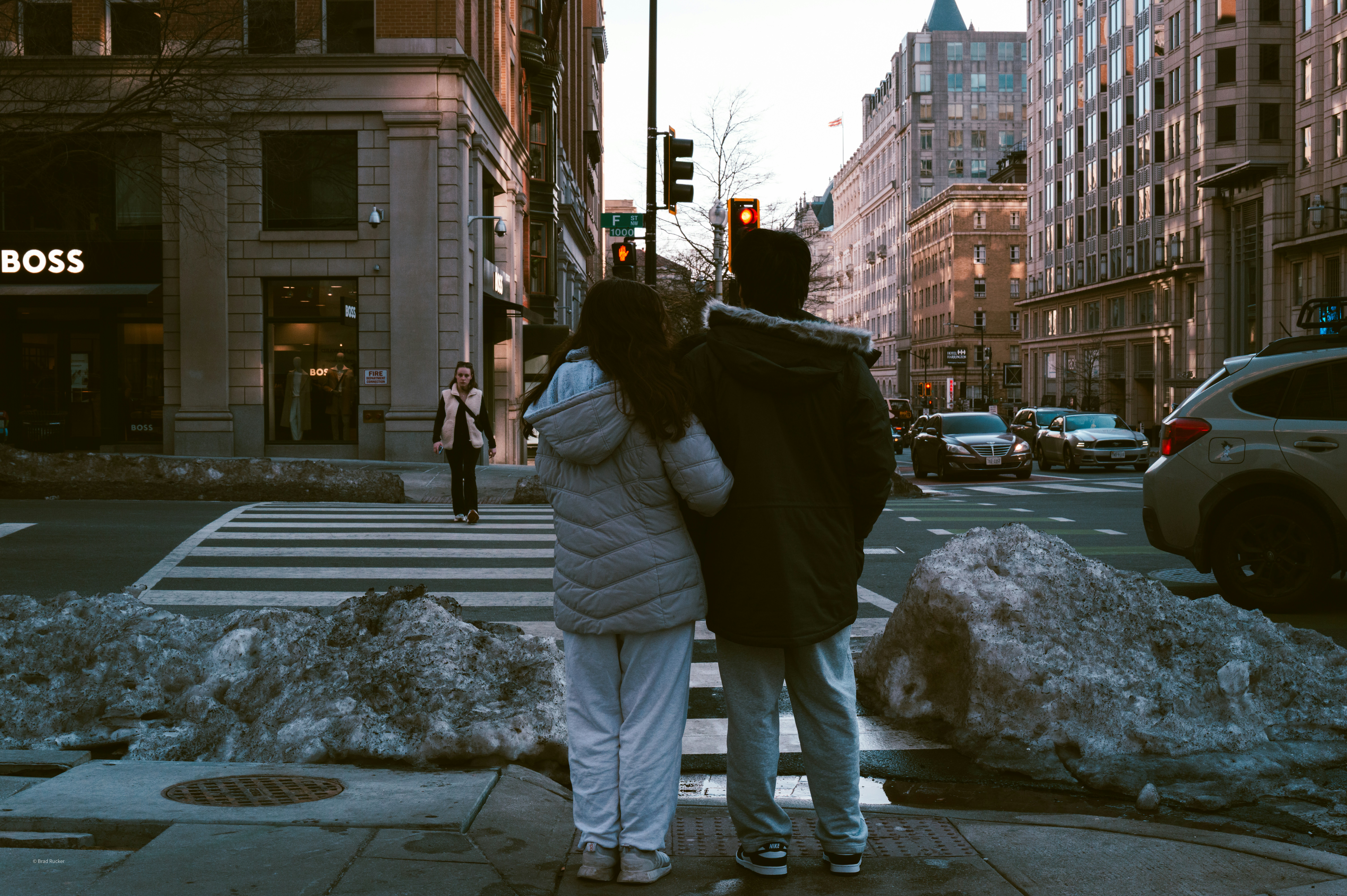 Couple standing at a snowy city crosswalk at dusk