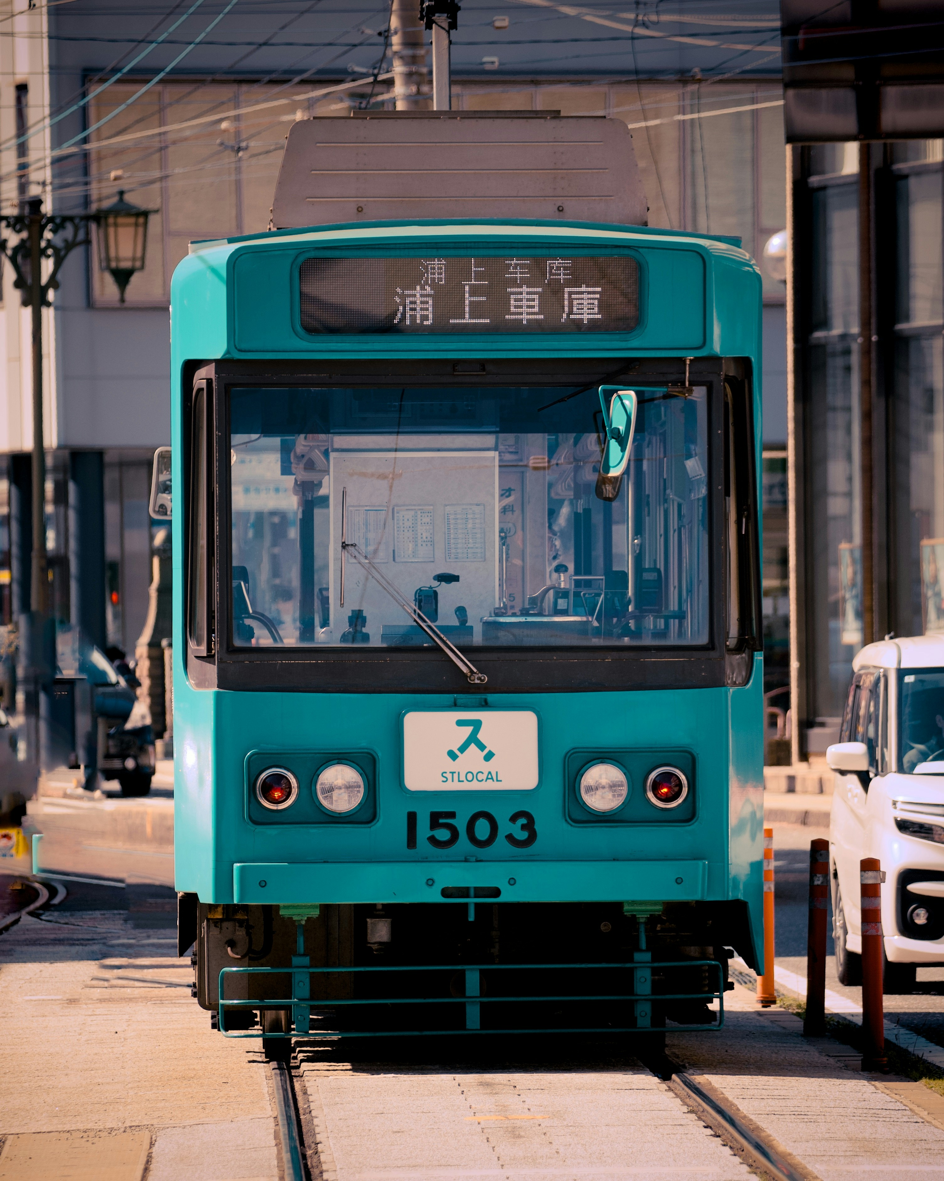 A turquoise tram on tracks in a city