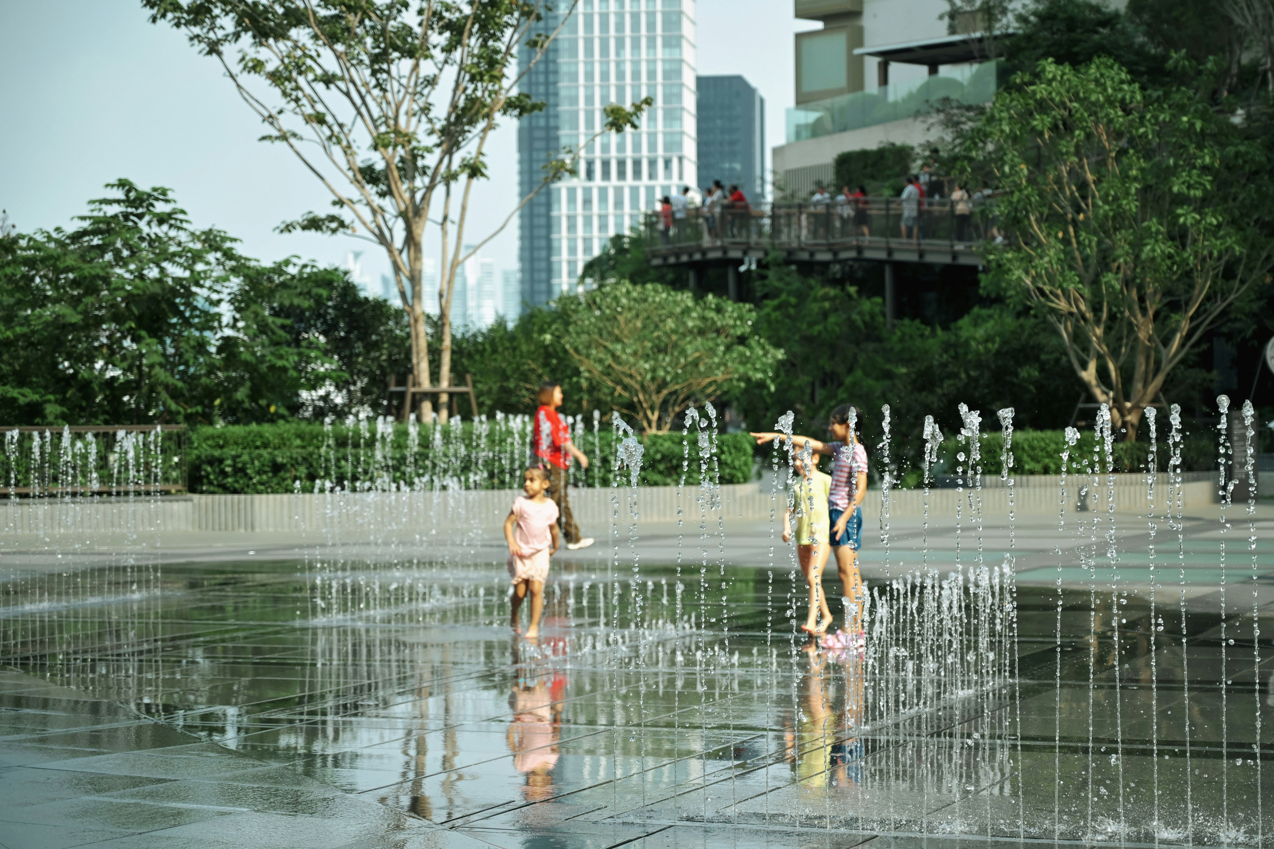 Children play in a modern water fountain park.