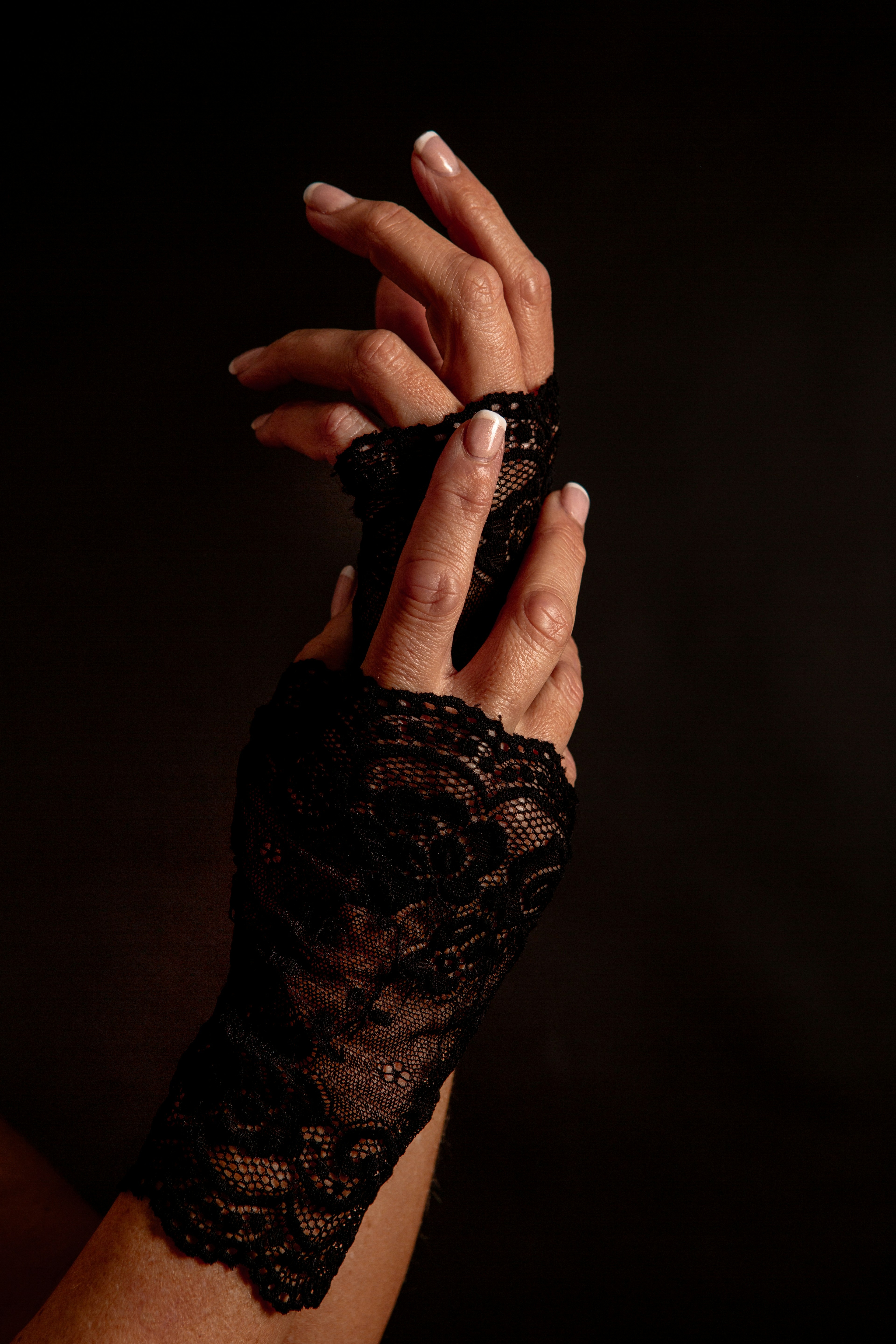 黒いレースの指なし手袋をはめた女性の手