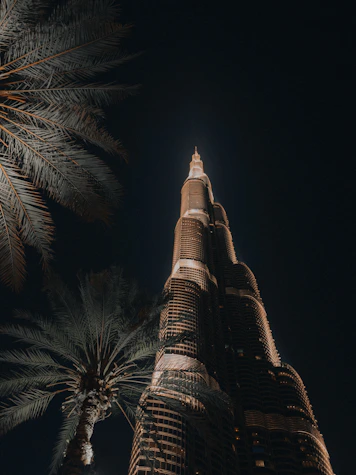 Burj khalifa skyscraper at night with palm trees