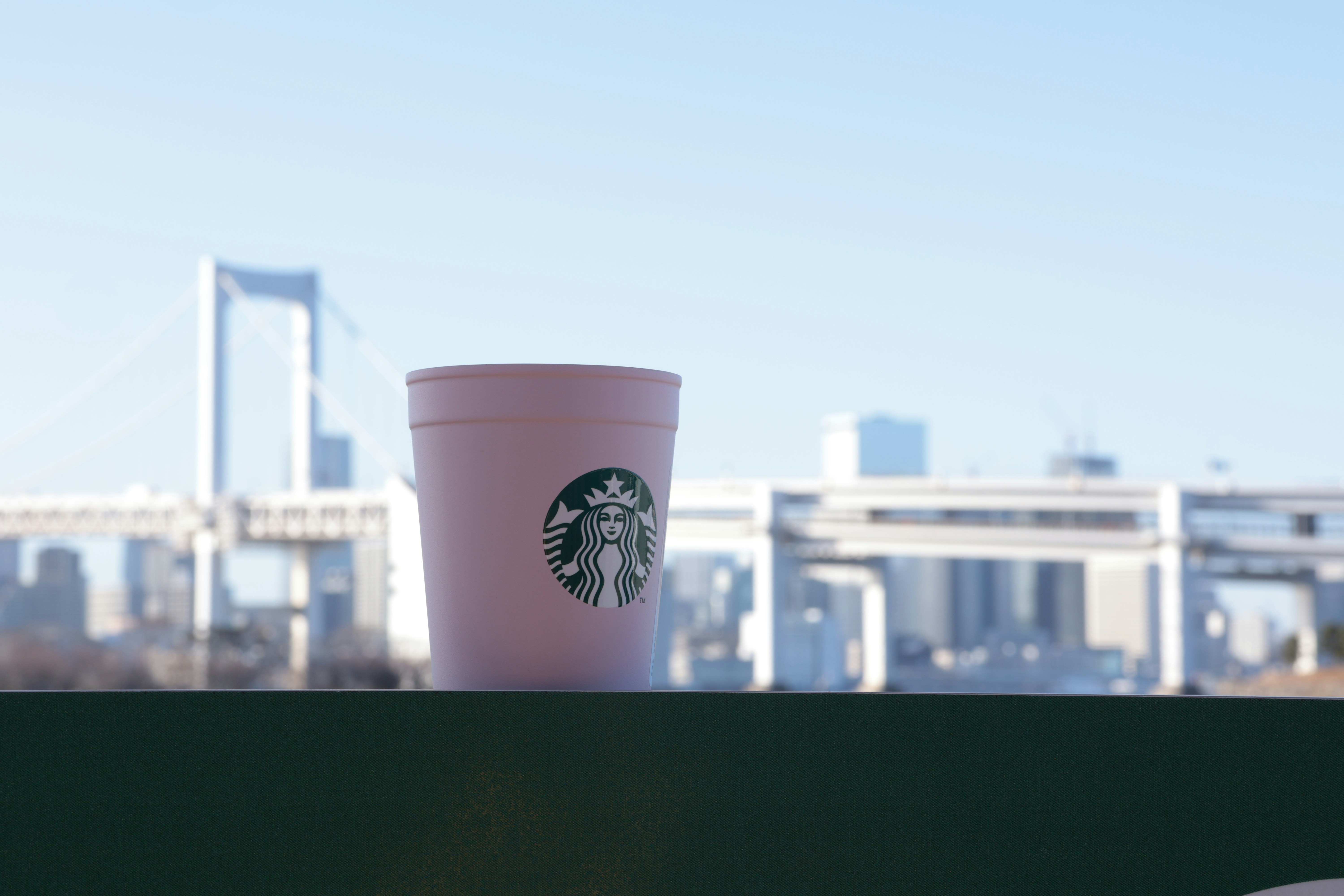 Pink starbucks cup with city and bridge background