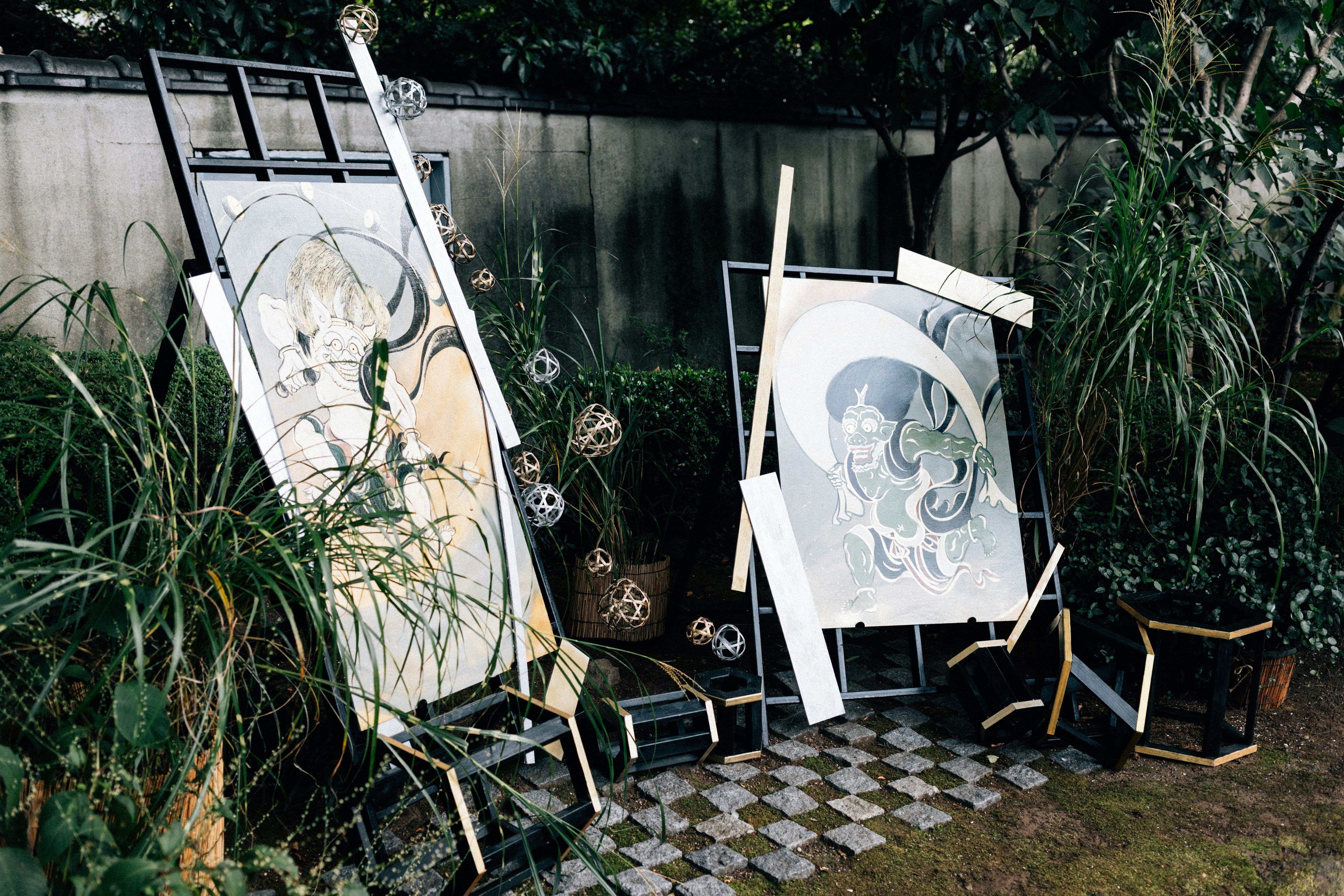 Two framed artworks leaning in a garden