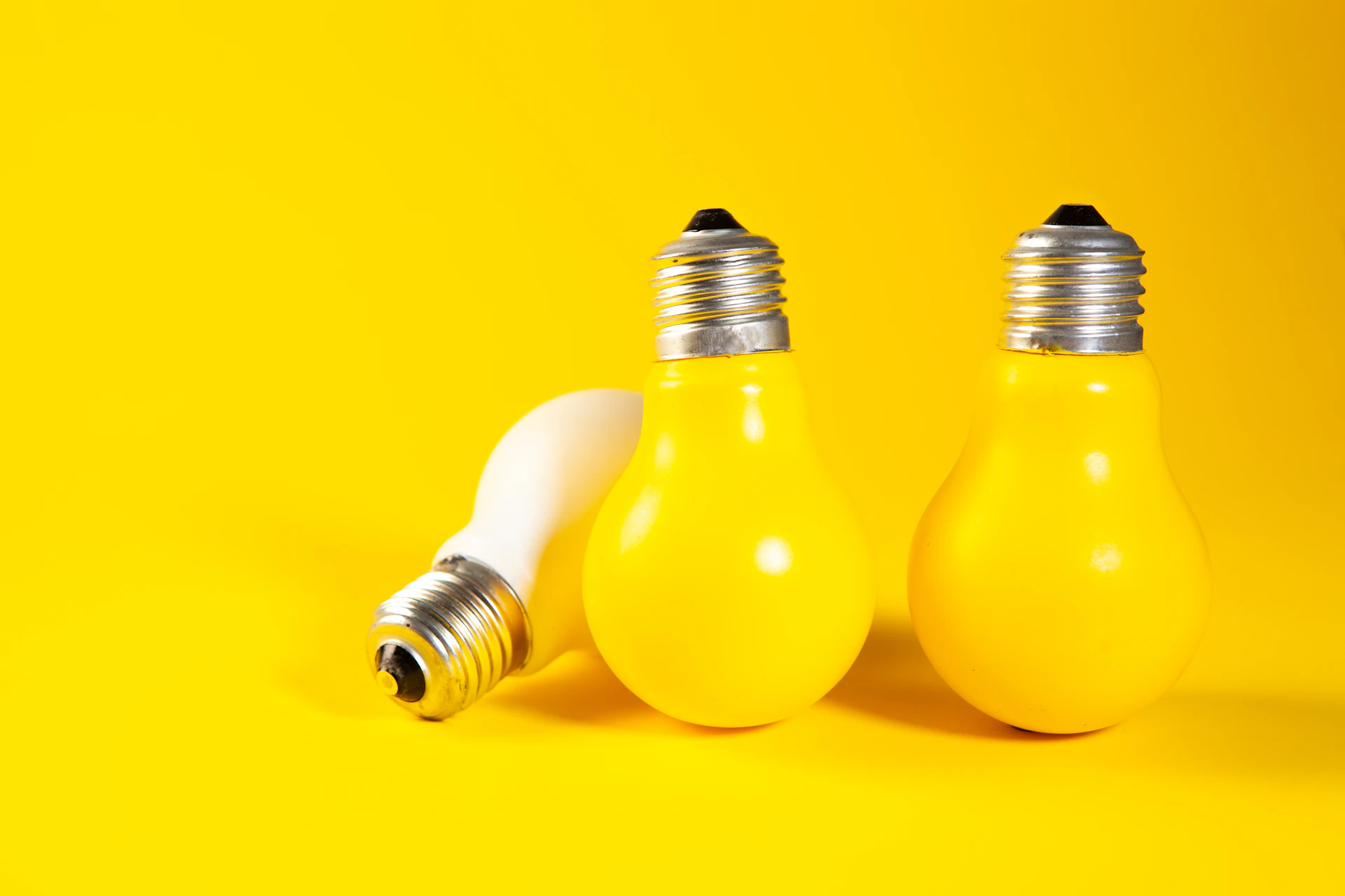 Three yellow light bulbs on a yellow background.
