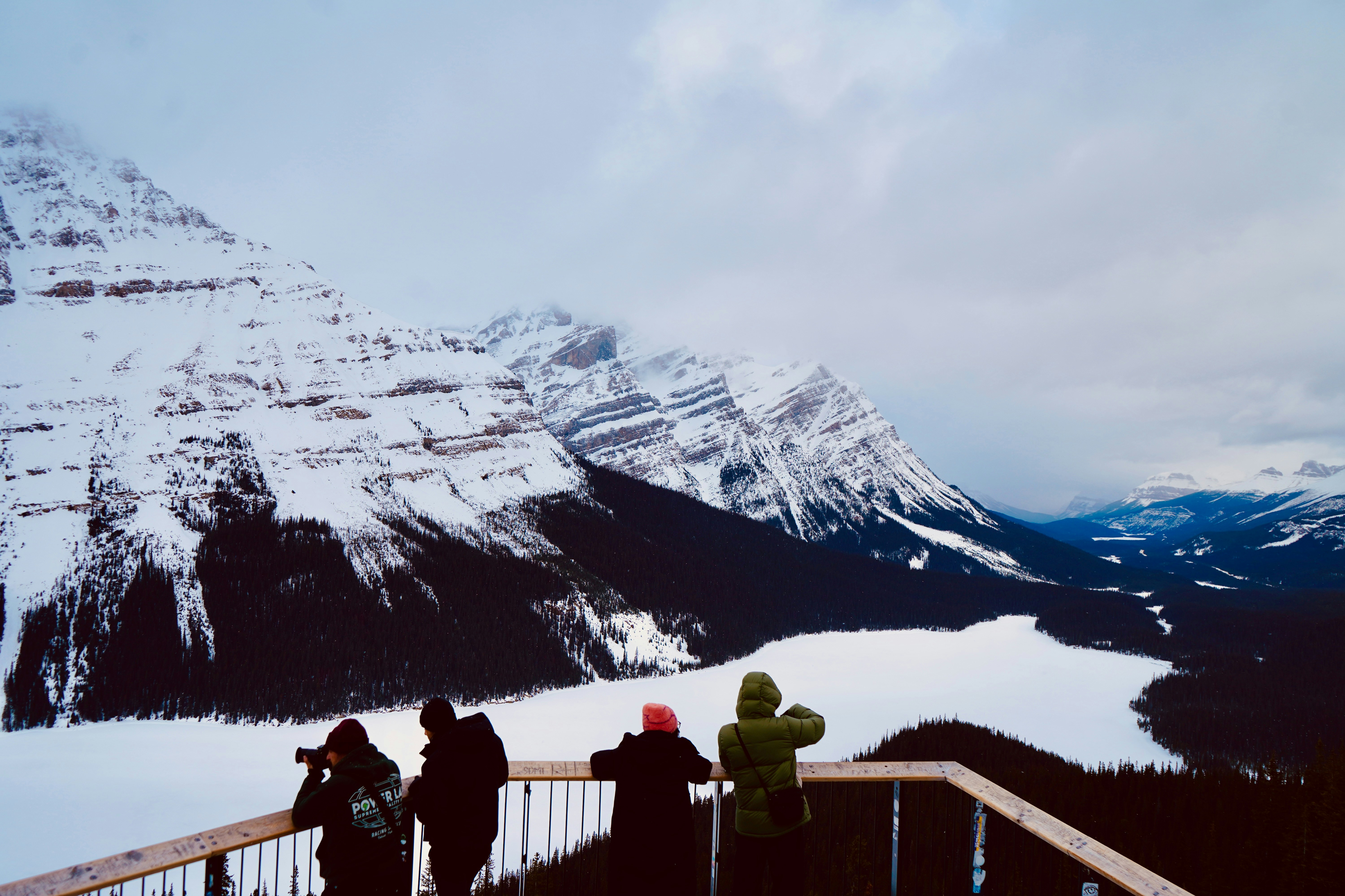 People admire snowy mountains and frozen lake