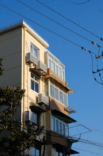 A tall building with multiple windows and air conditioners.