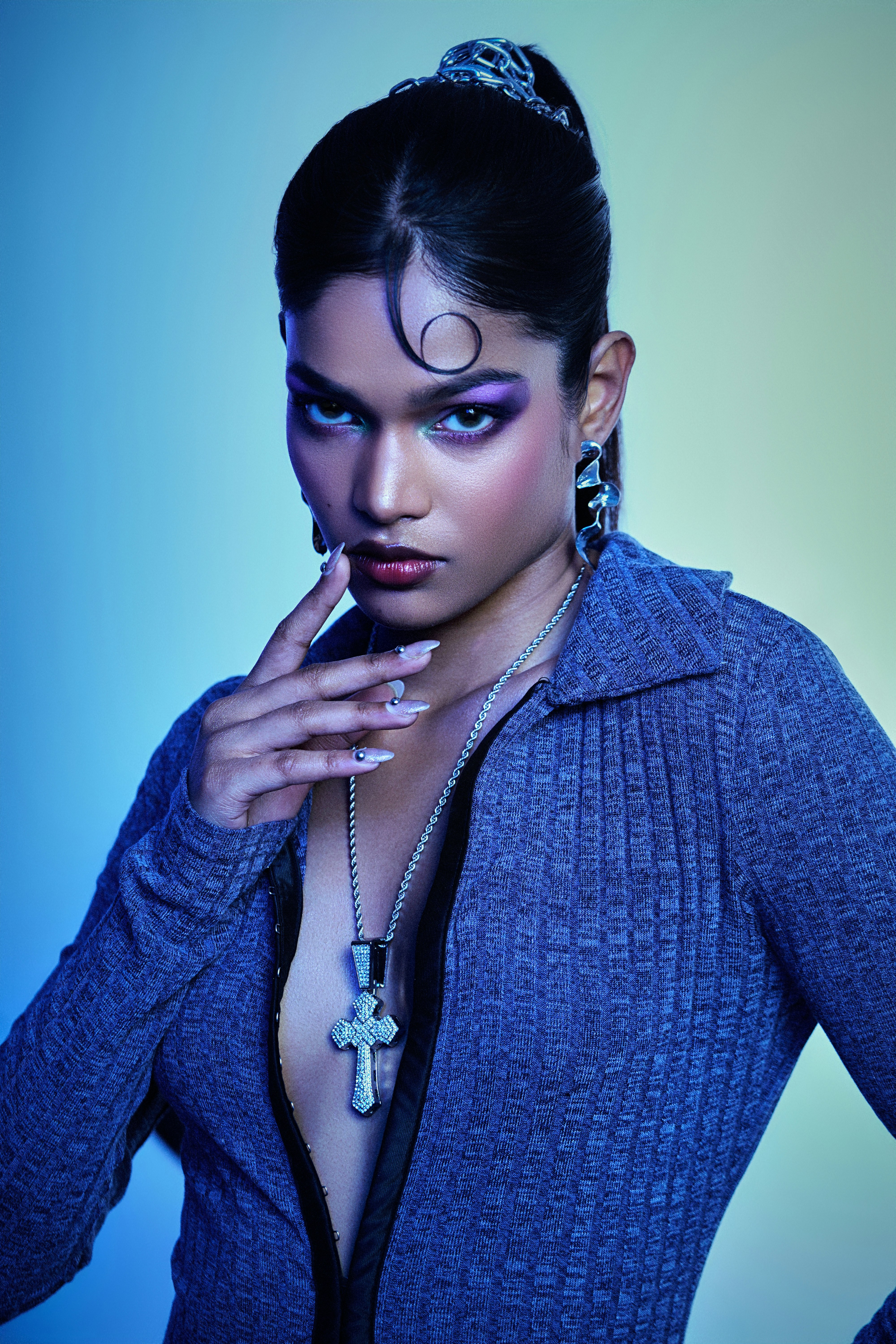 A woman with dramatic makeup and jewelry poses.