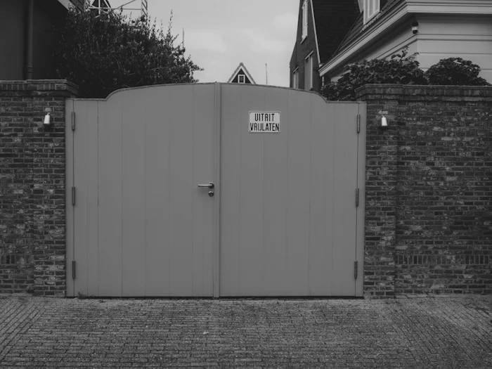 Closed gray automatic driveway gate set in a brick wall